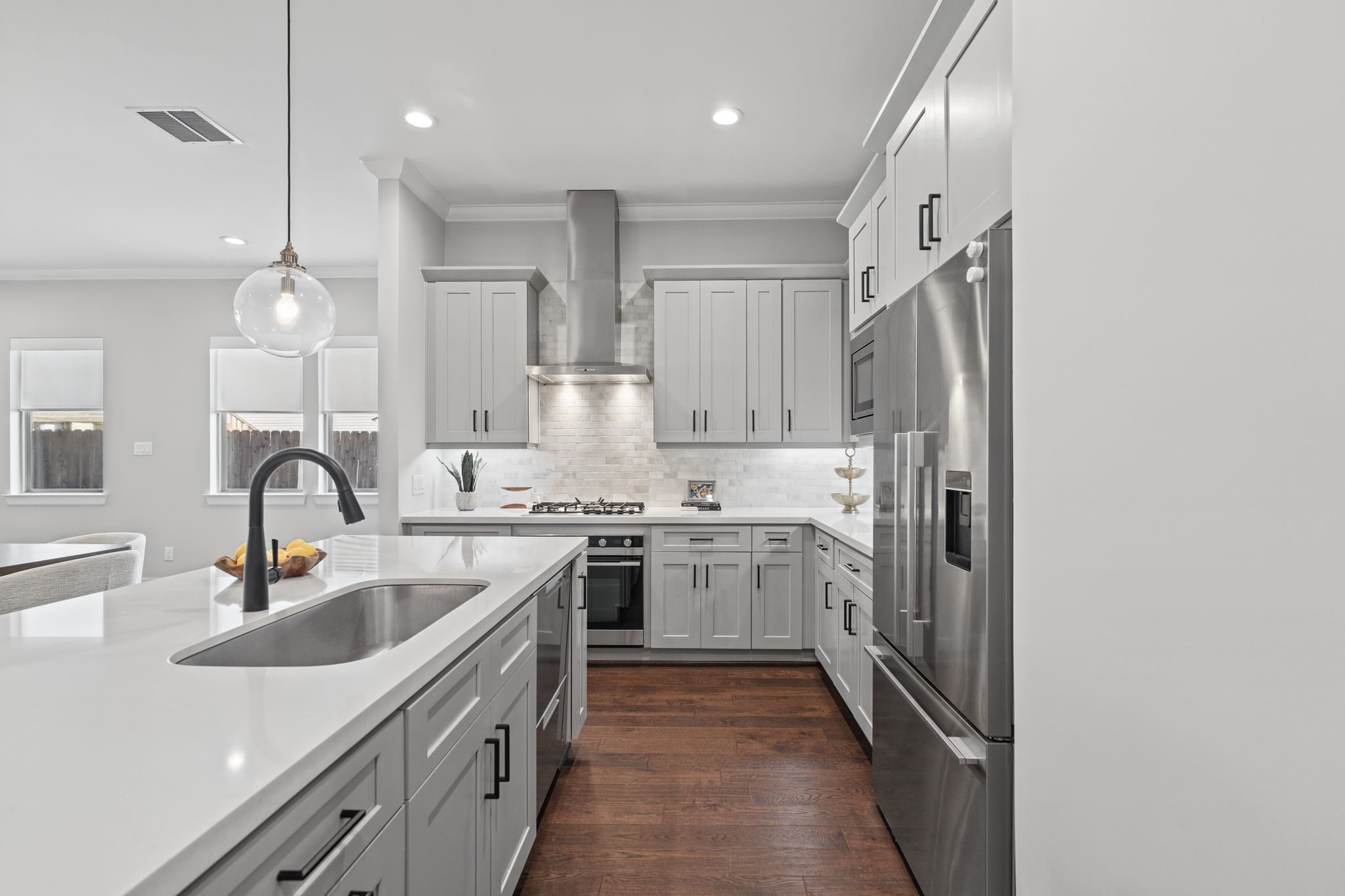 An expansive island anchors the kitchen, offering generous preparation space, casual seating, and a polished focal point for gathering and entertaining.