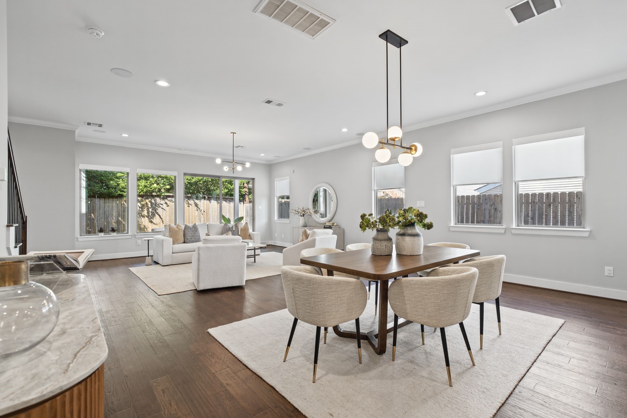 A sophisticated dining space pairs a warm wood table with upholstered seating and statement lighting, seamlessly connecting to the surrounding living areas.