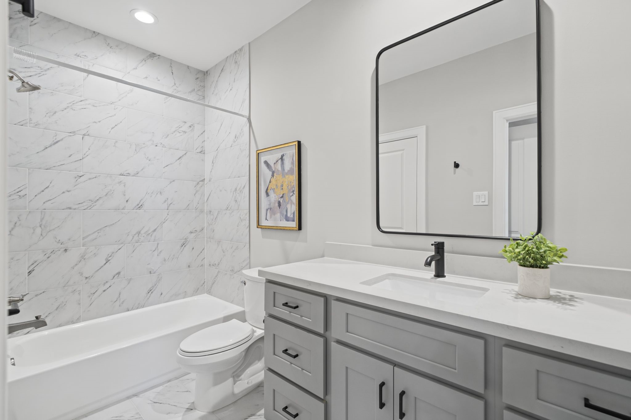 Another spacious secondary bath with contemporary fixtures, a streamlined vanity, and elegant marble-look tile create a fresh, timeless finish in the secondary bath.
