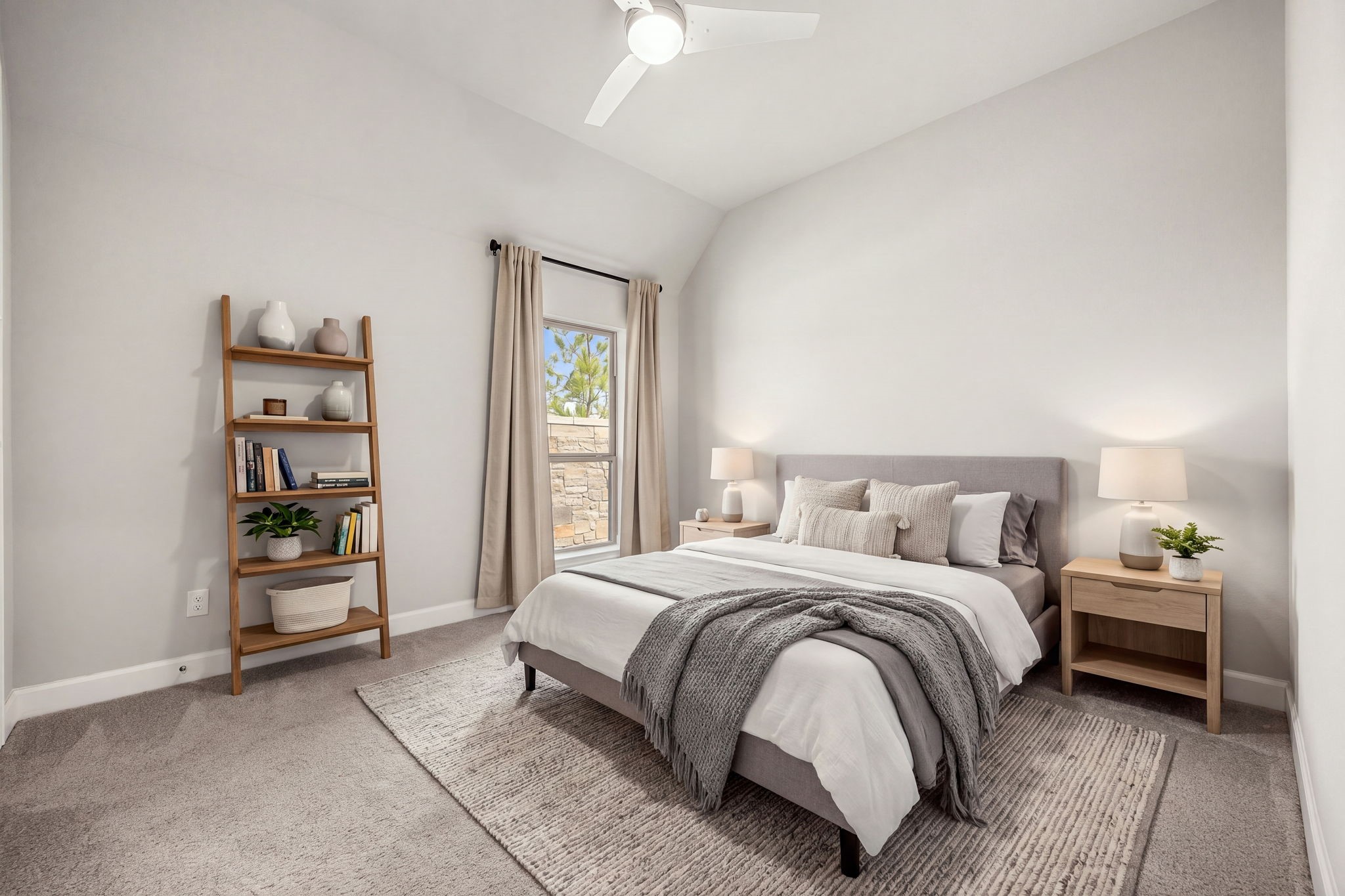 Another beautifully appointed secondary bedroom features an impressive vaulted ceiling that elevates the space, giving it a bright and expansive feel. Complete with plush carpeting, a large single window, and a modern white ceiling fan, this room provides a comfortable and stylish retreat for family or guests.