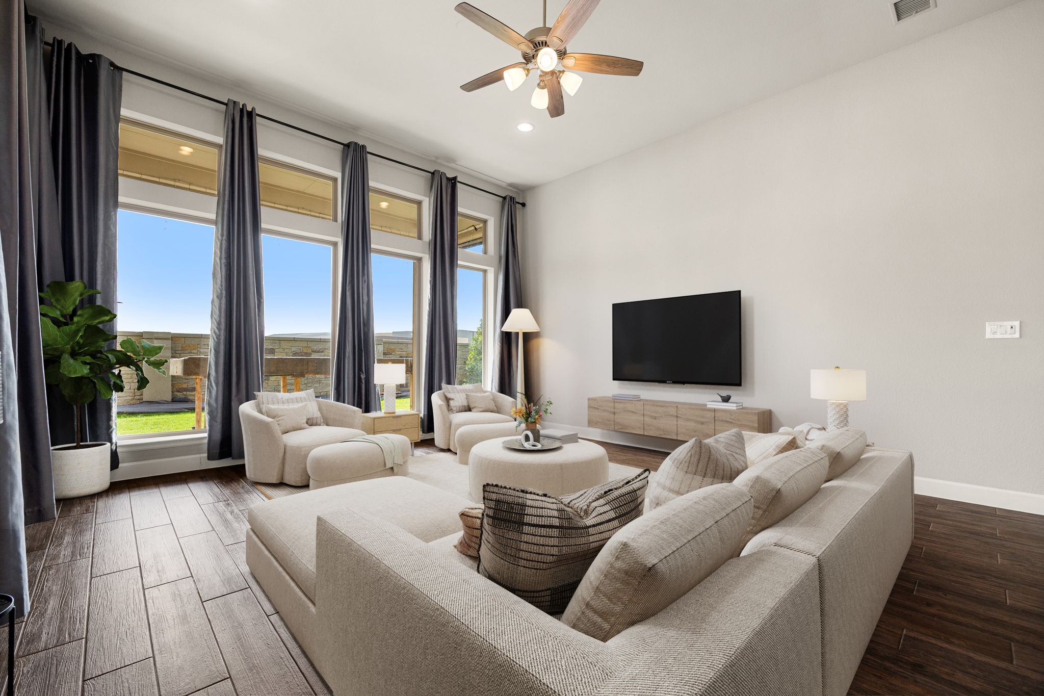 Additional view of this magnificent family room showcasing the sheer volume of the space, anchored by towering 13-foot ceilings and a center-mounted ceiling fan for optimal comfort. The spectacular wall of floor-to-ceiling windows floods every corner with natural light, offering plenty of space to arrange plenty of seating and entertainment centers without ever feeling crowded. *Virtually Staged
