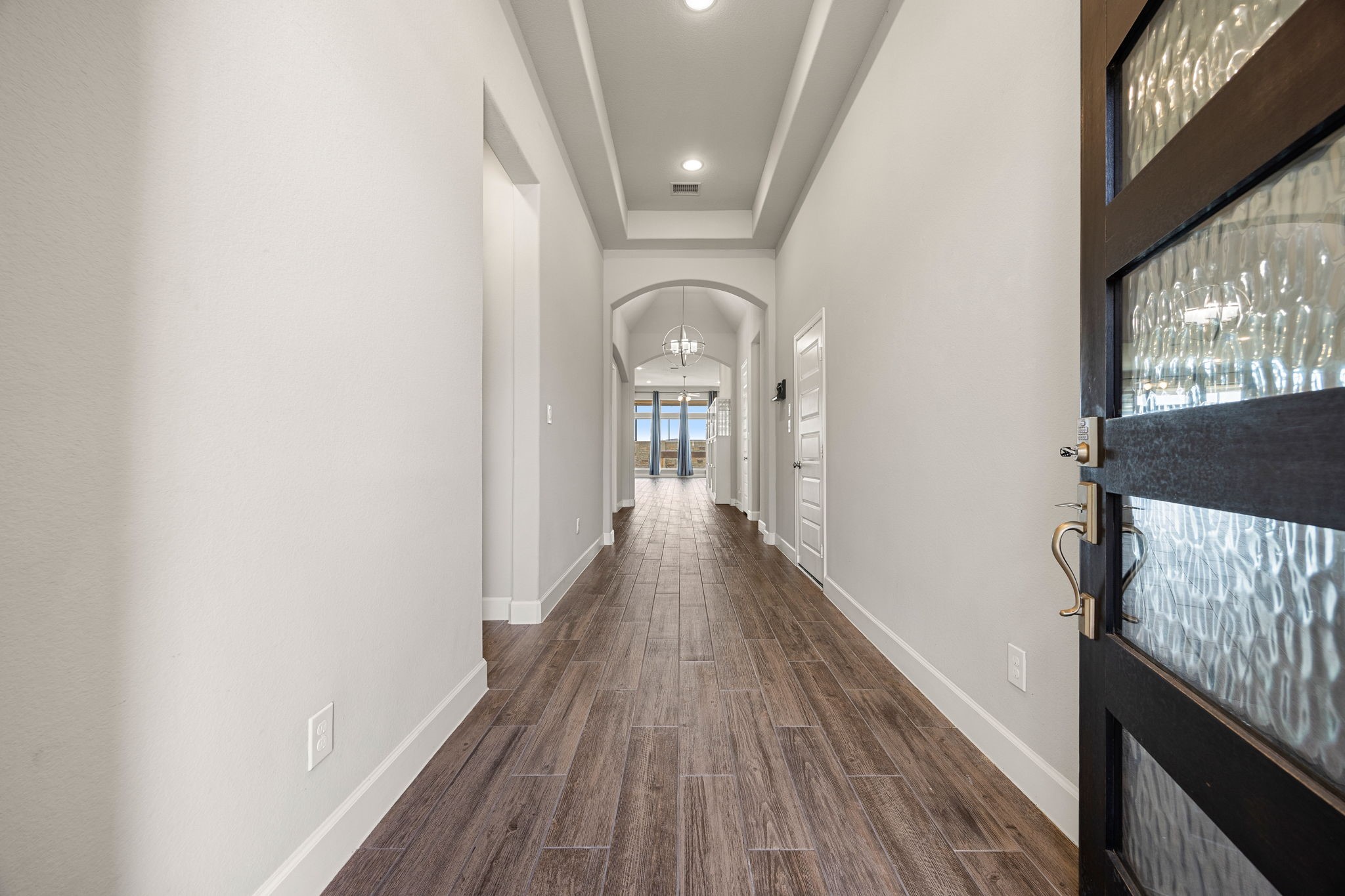 A grand first impression awaits as you step through the beautiful glass-paneled front door. An extended entryway draws you in with soaring 12-foot tray ceilings, recessed lighting, and elegant wood-look tile flooring that guides you effortlessly into the heart of the home. A grand first impression awaits as you step through the beautiful glass-paneled front door. An extended entryway draws you in with soaring 12-foot tray ceilings, recessed lighting, and elegant wood-look tile flooring that guides you effortlessly into the heart of the home.