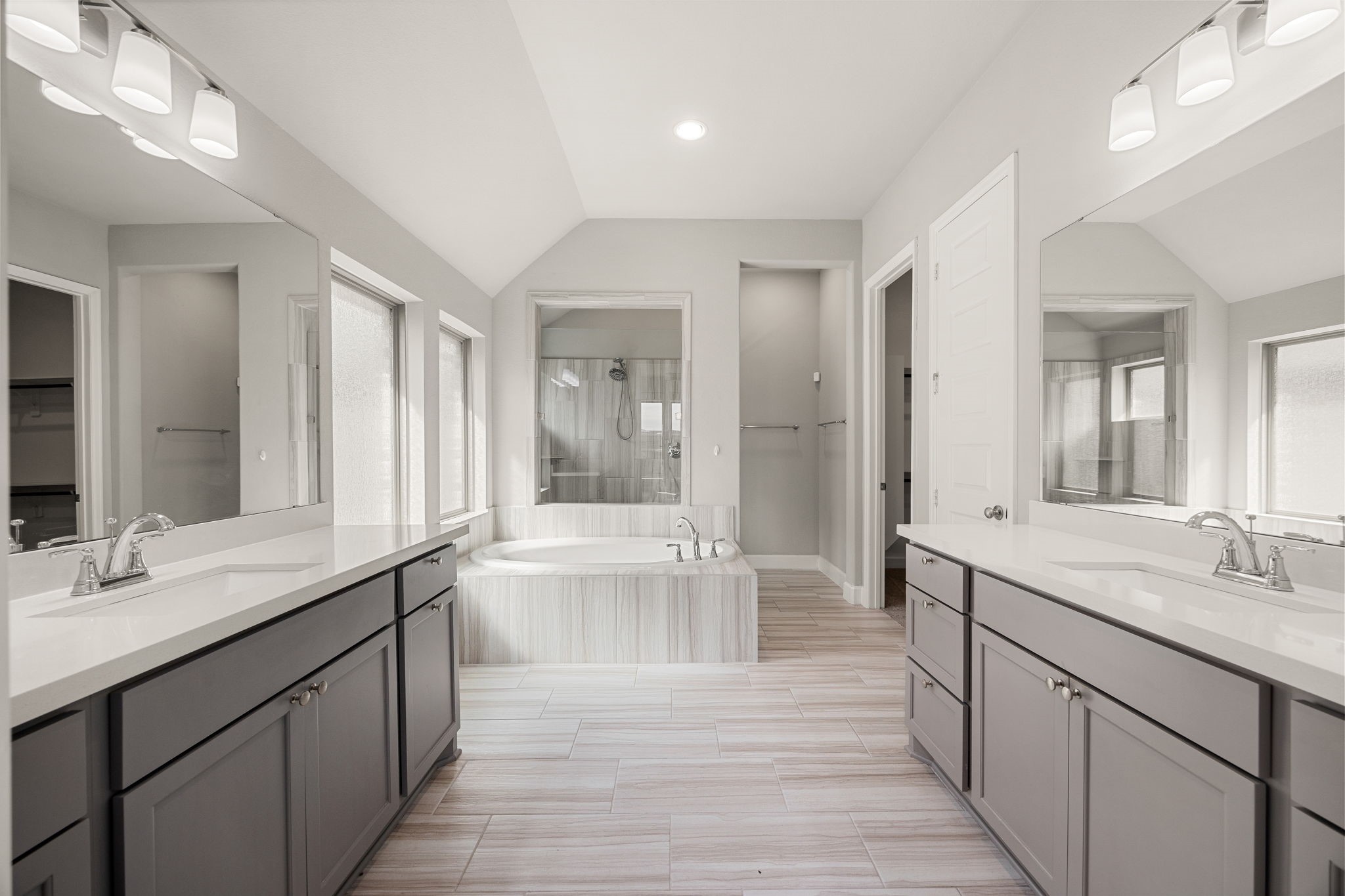 Daily routines feel like a resort getaway in this bright, expansive primary bath. The distinct his-and-hers vanities provide abundant personal counter space and storage, while the sloped ceiling lines and soft frosted windows wash the room in calm, natural light. It is the perfect, private sanctuary to unwind.