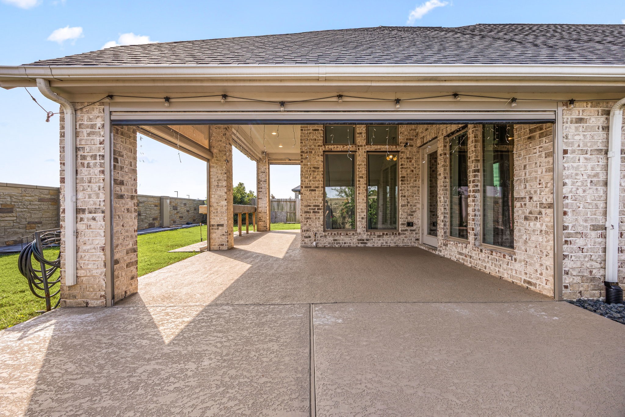 Outdoor entertainment goals achieved! The textured concrete floor extends straight out to the open lawn. Enclosed by your secure stone privacy wall, this massive covered space offers all the room you need for a complete outdoor kitchen setup and premium lounge furniture.