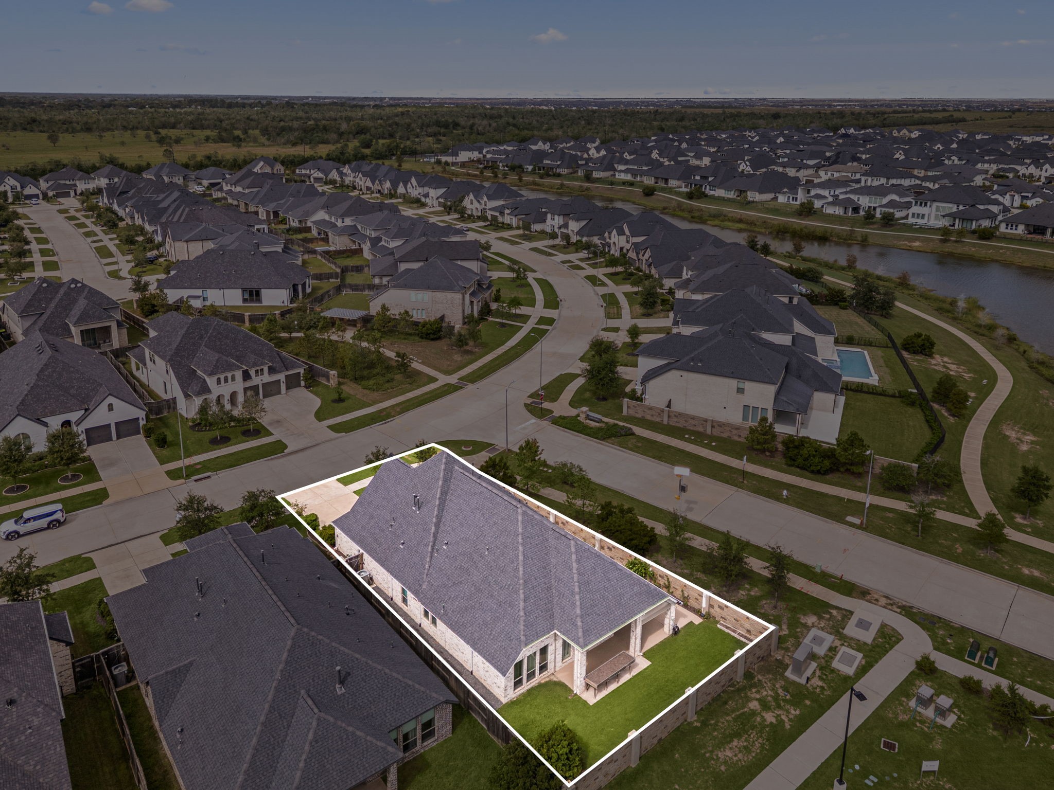 This birds-eye view perfectly captures the home's premier corner lot position within Cross Creek Ranch. Outlined to show its generous boundary lines, the property benefits from an expansive, manicured lawn with a stone privacy fence and no direct rear neighbors, offering a rare sense of openness and breathing room in a master-planned community.