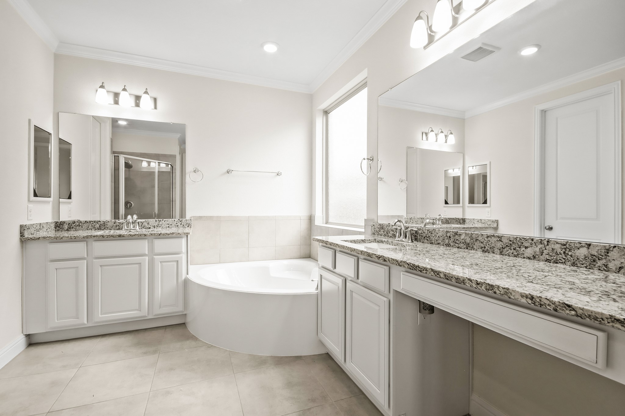 Primary bathroom has large countertop area with vanity lighting.