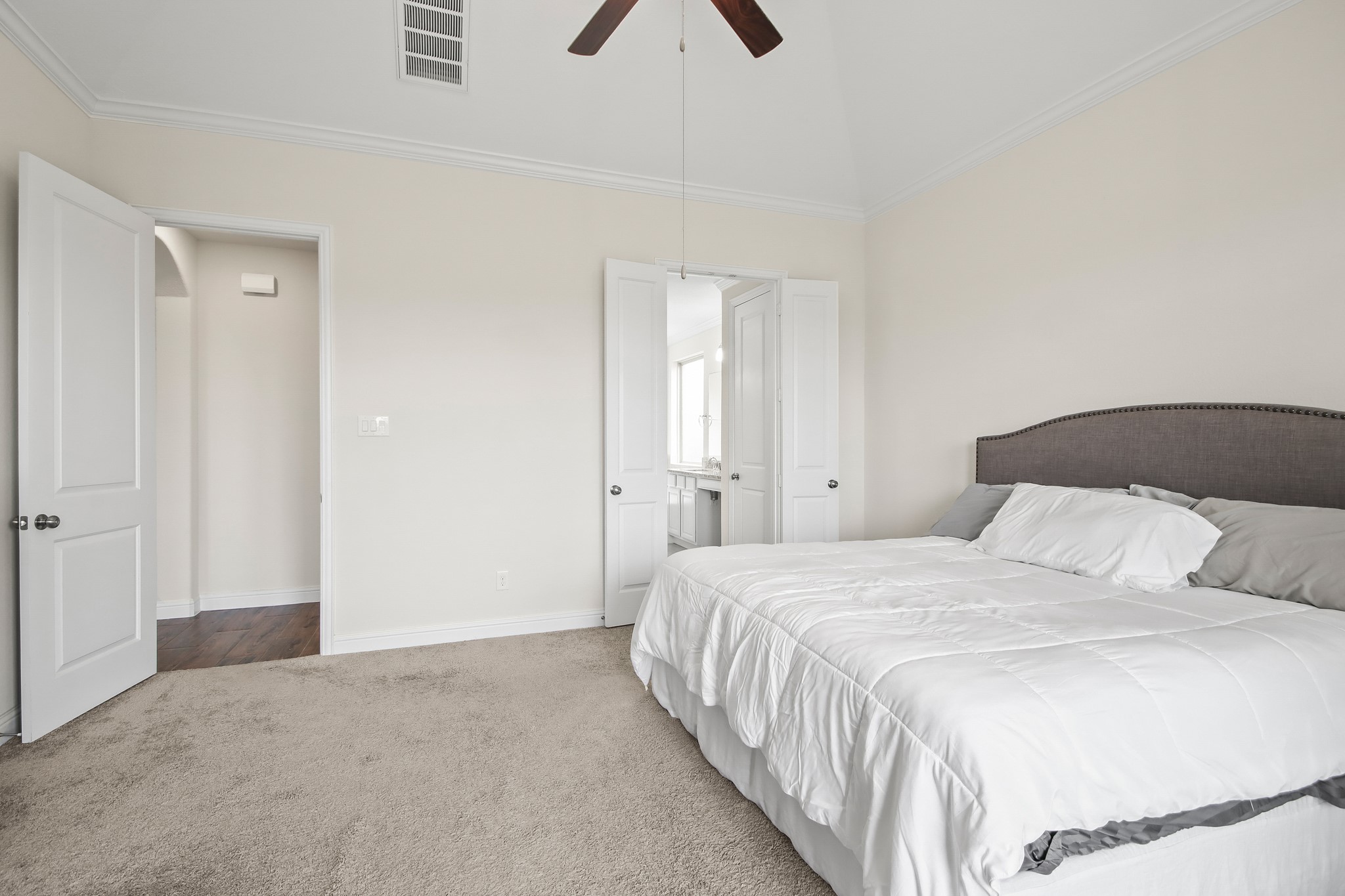 Primary bedroom with neutral carpet, ceiling fan and large walk in closet.