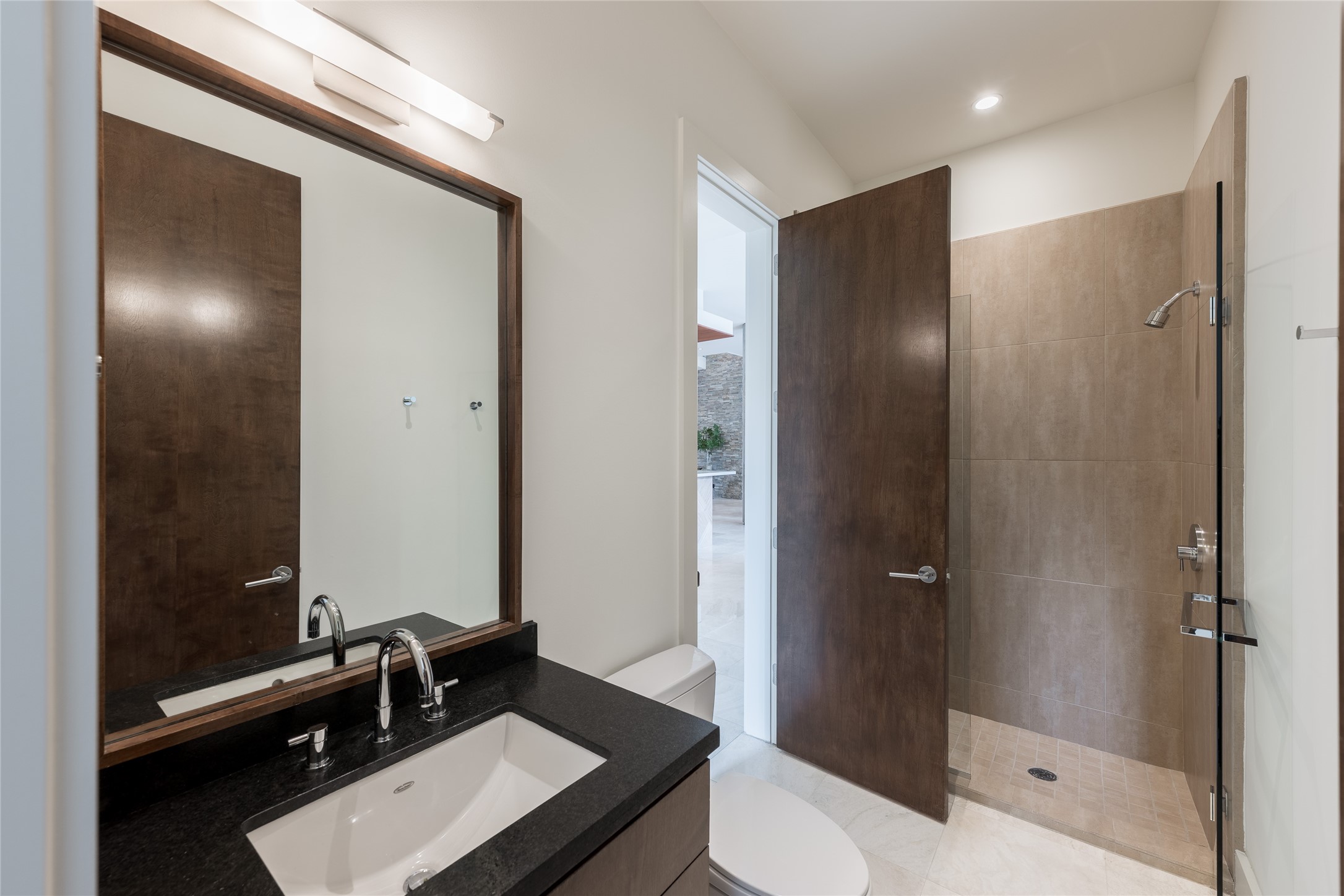 One of two full bathrooms on the first floor, this space also serves as the dedicated pool bath with convenient access from the outdoor living area. A walk-in shower allows guests to transition directly from the pool without moving through the main living spaces.