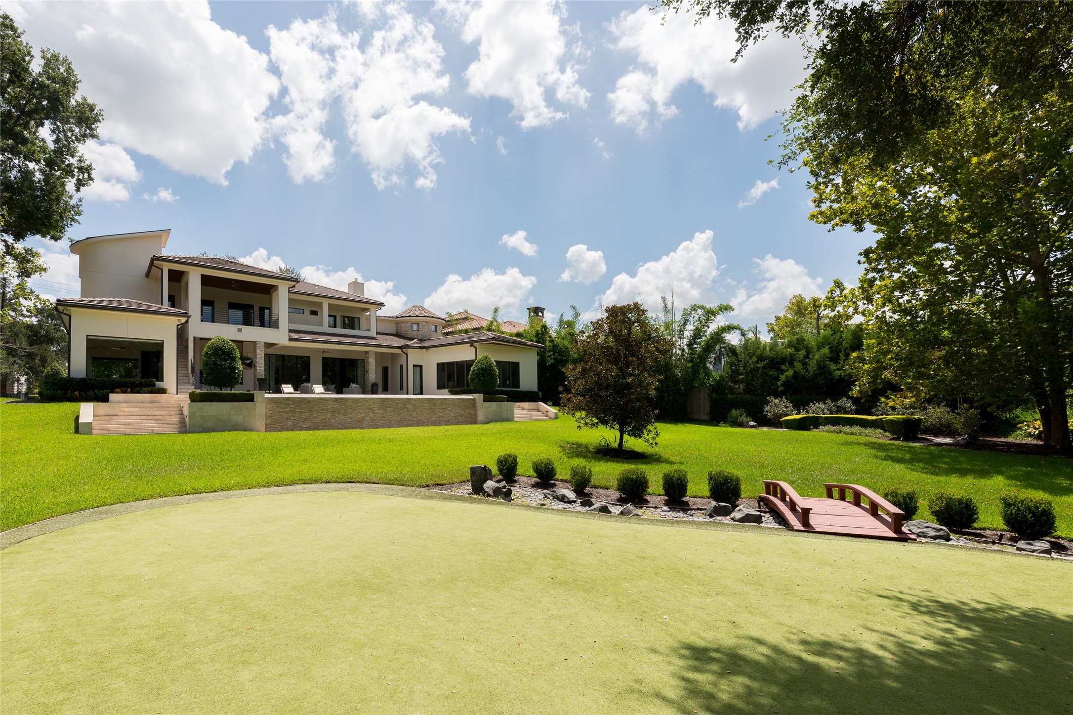 An expansive lawn creates a remarkable sense of openness behind the residence, anchored by a private putting green and framed by mature landscaping. A setting that feels more like a private estate than a home positioned just moments from the heart of Houston