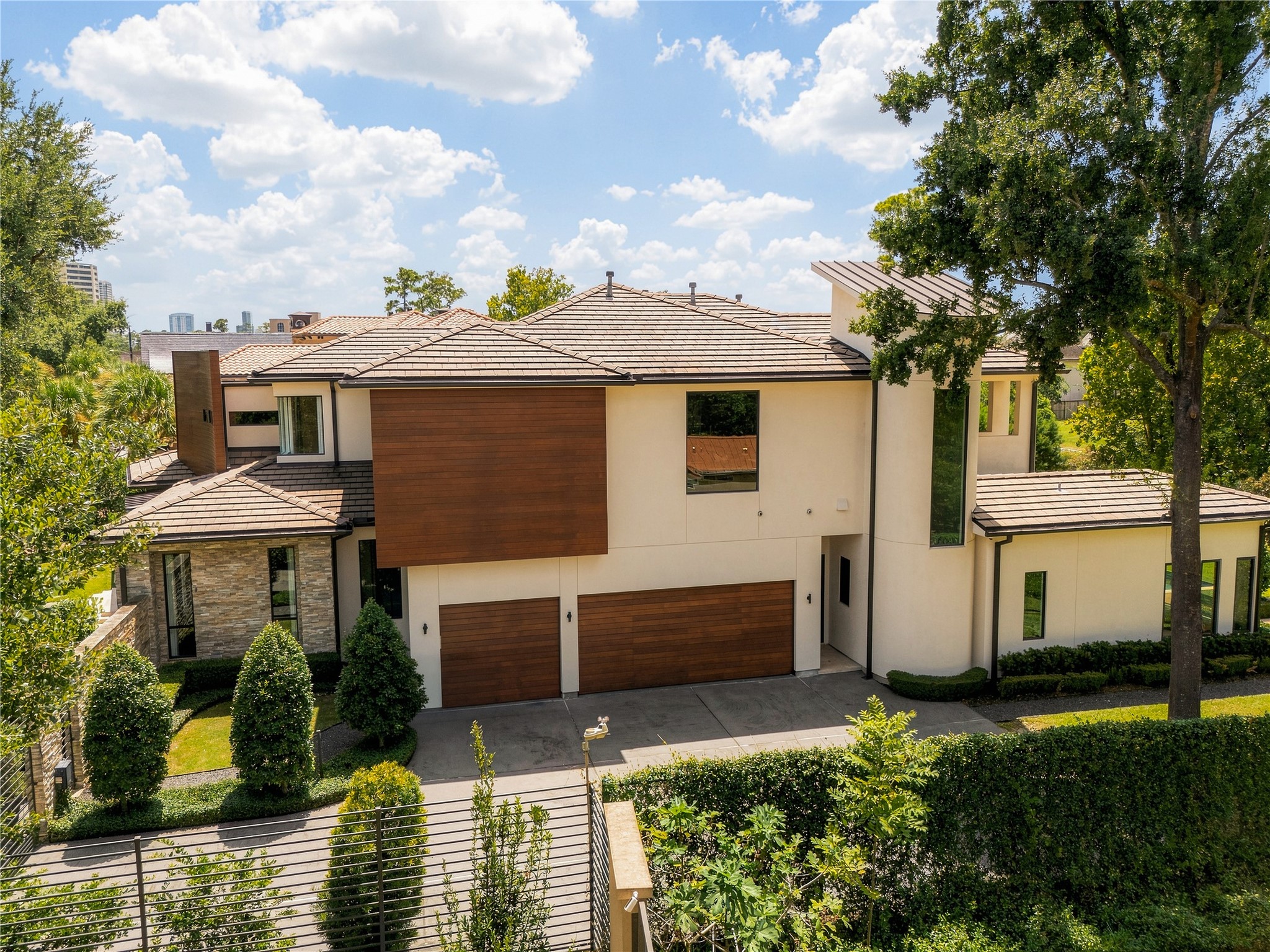 The side elevation reveals the homes material driven architecture, where rich mahogany accents, three-coat traditional hard-coat stucco, stacked stone and a natural slate roof create a warm contrast of texture and form.
