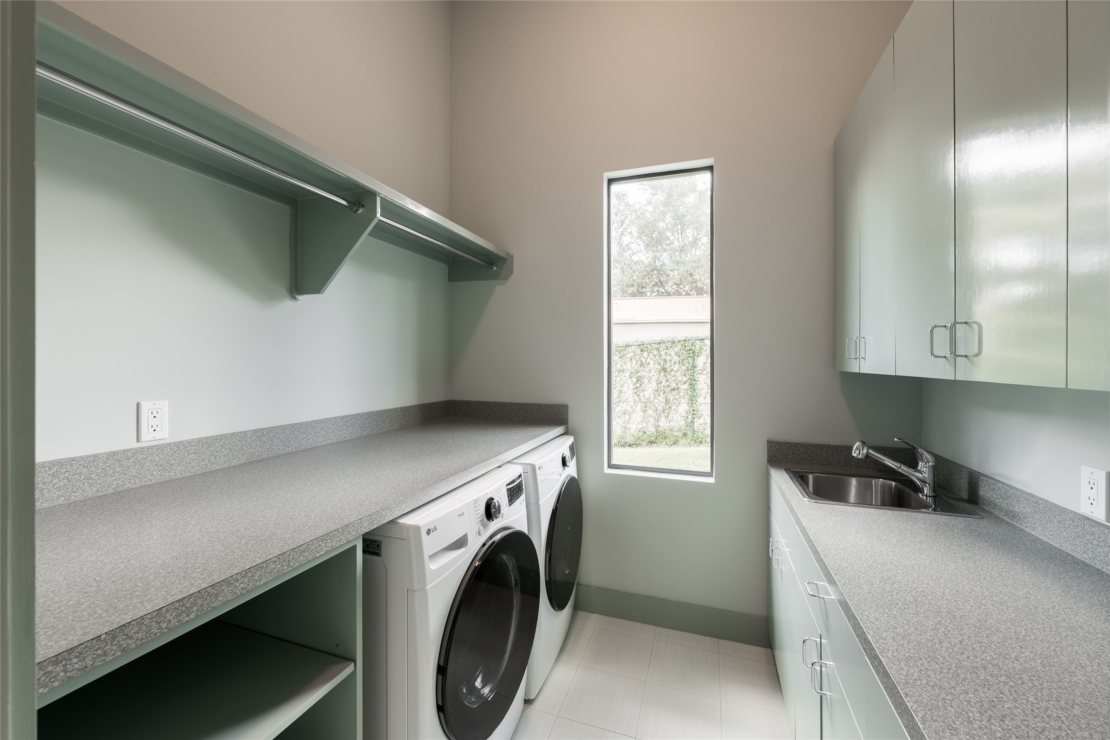 Located on the first floor, the utility room offers generous counterspace, extensive cabinetry and open shelving for everyday organization. Dual washer and dryer units provide added capacity, while natural light keeps the workspace bright and functional.