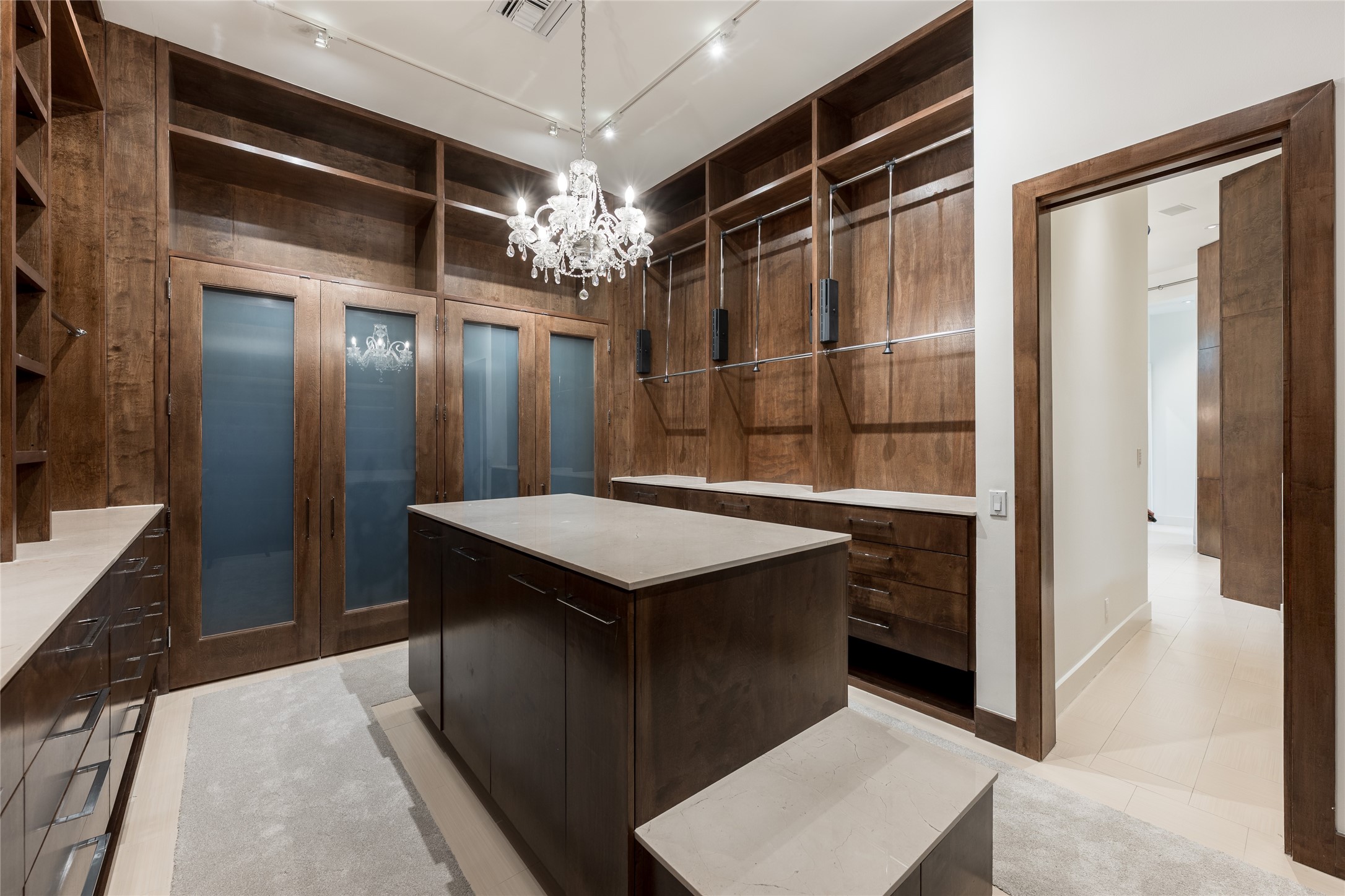 The expansive primary closet is fully custom built with floor-to-ceiling cabinetry, integrated lighting and extensive hanging and storage space. A large center island adds additional storage and counter space, creating a highly functional dressing environment within the primary suite.
