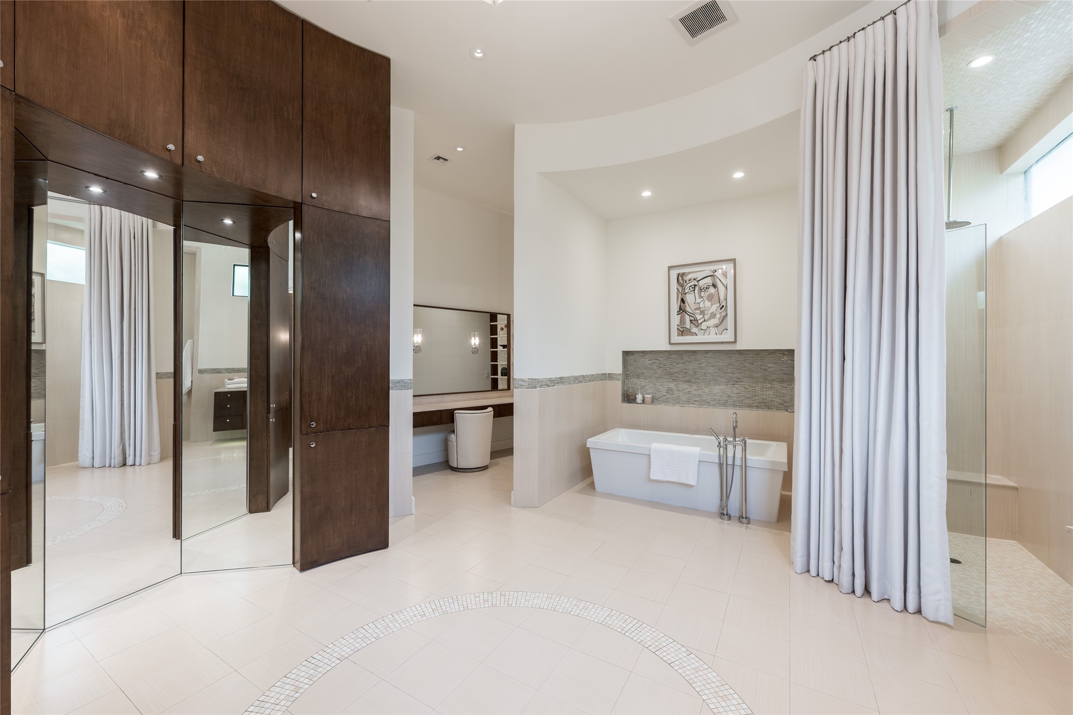 A full mirrored dressing and vanity area to the left is complemented by additional custom cabinetry, creating a dedicated space for personal preparation.