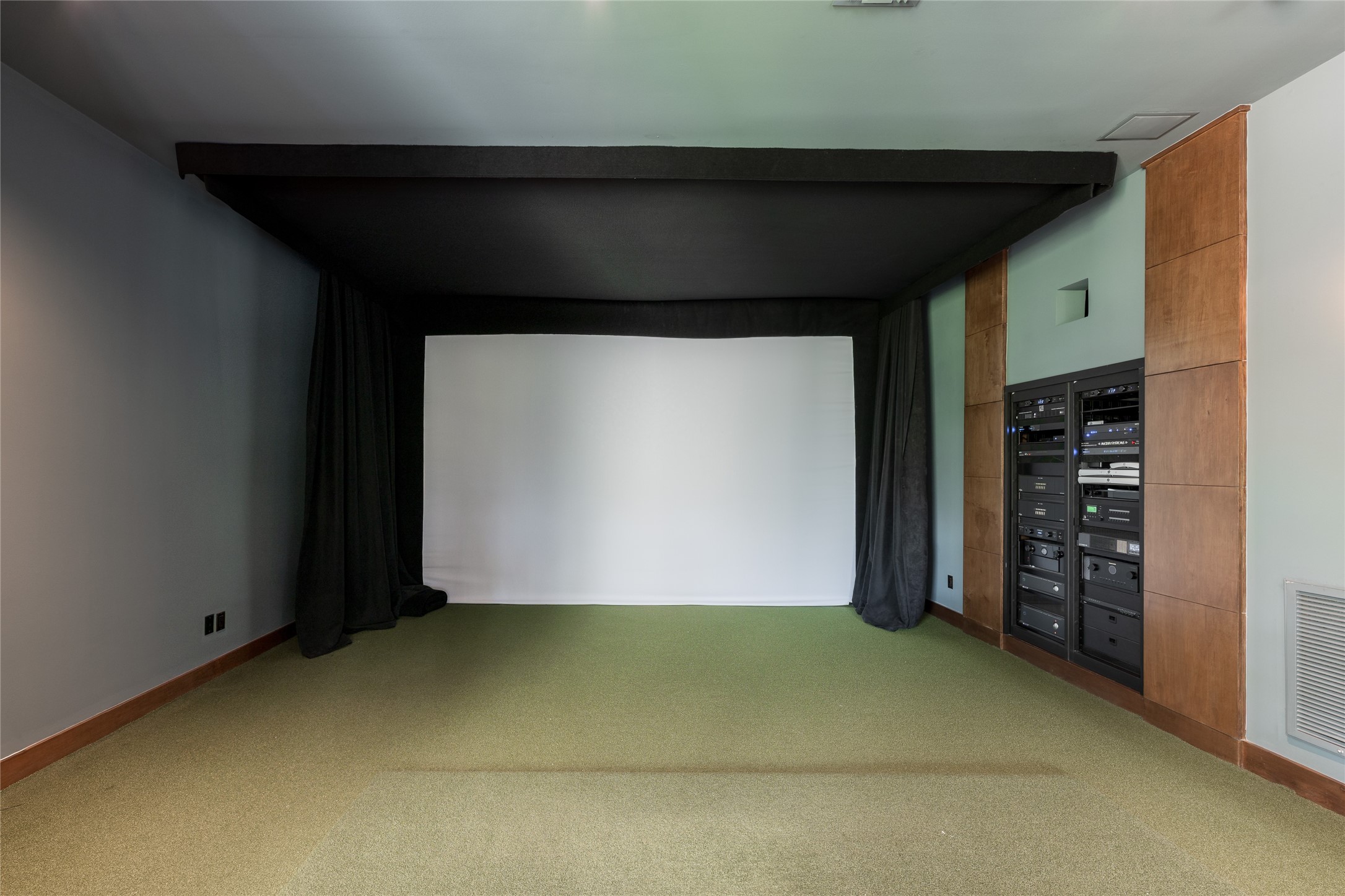 The golf simulator room also serves as the technology hub for the residence, housing the AV rack for the homes Crestron automation system. Centralized controls integrate the homes audio, video and automated features while keeping the equipment discreetly contained.