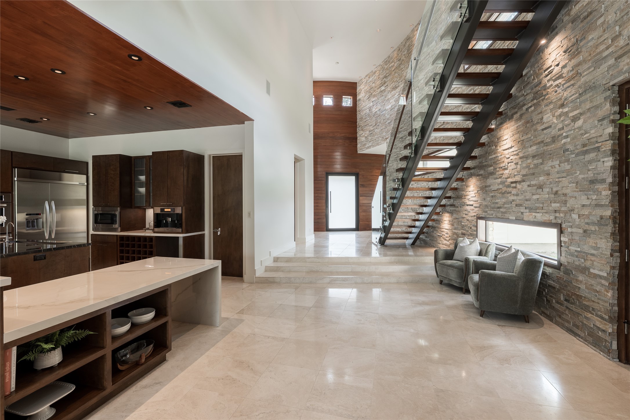 Just beyond the kitchen, a flexible sitting area creates an intimate space for conversation while maintaining the homes open flow. Its generous proportions also offer an ideal setting for a baby grand piano, creating an elegant transition between the kitchen and foyer