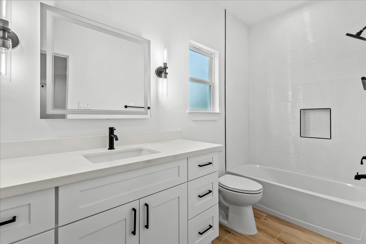 Unit A - Secondary bathroom features a tub/shower combination accented with elegant black fixtures and a modern LED vanity mirror, creating a stylish and functional space for family and guests.