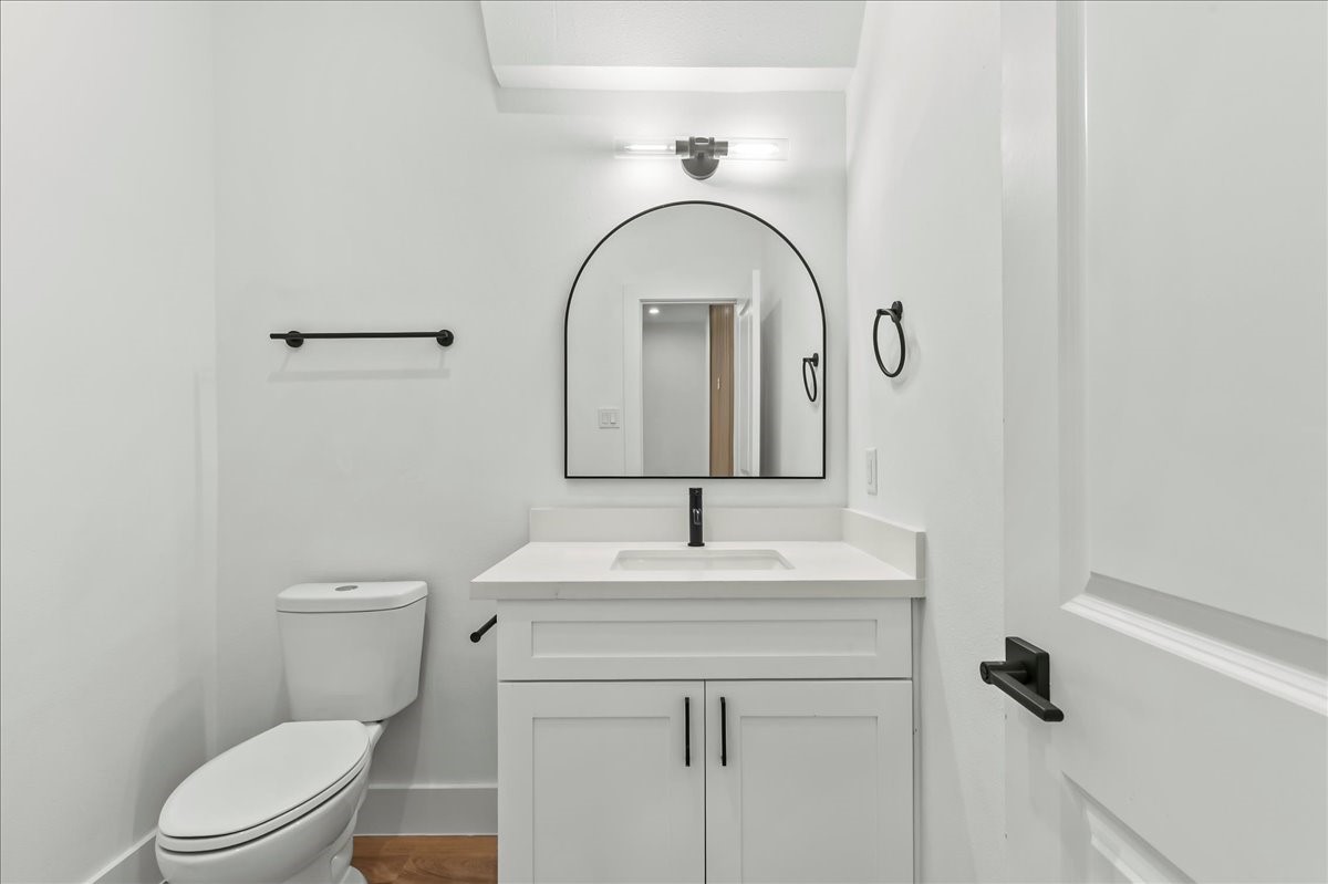 Unit B - Spacious half bath featuring white quartz countertops, white cabinets, and modern fixtures.