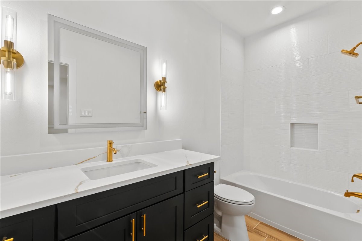 Unit A - Secondary bathroom features a tub/shower combination accented with elegant gold fixtures and a modern LED vanity mirror, creating a stylish and functional space for family and guests.