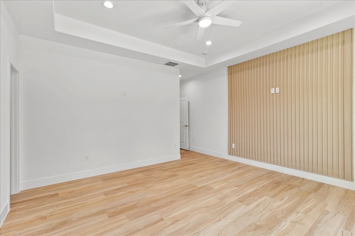 Unit A - Spacious primary suite featuring a beautiful neutral-toned accent wall that perfectly complements the wood-look flooring, elegant coffered ceiling, and a remote-controlled ceiling fan.Accent Wall design may vary. Pictures are from a previous build.