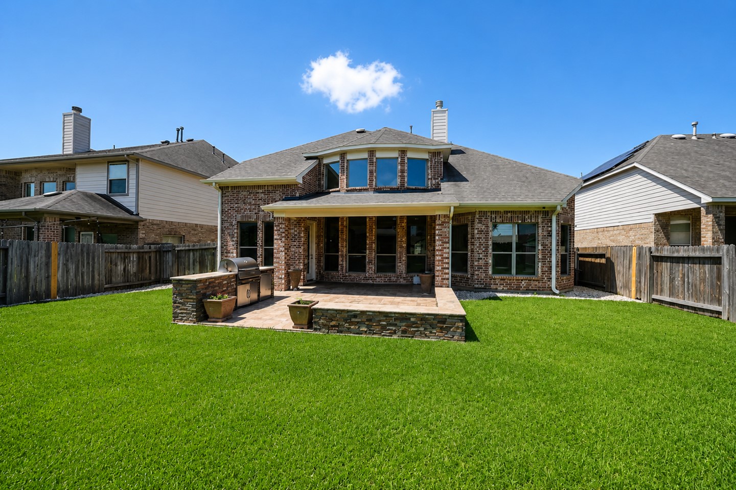 Charming brick home with a spacious, well-maintained backyard. Features a covered patio and built-in grill area, perfect for outdoor entertaining.