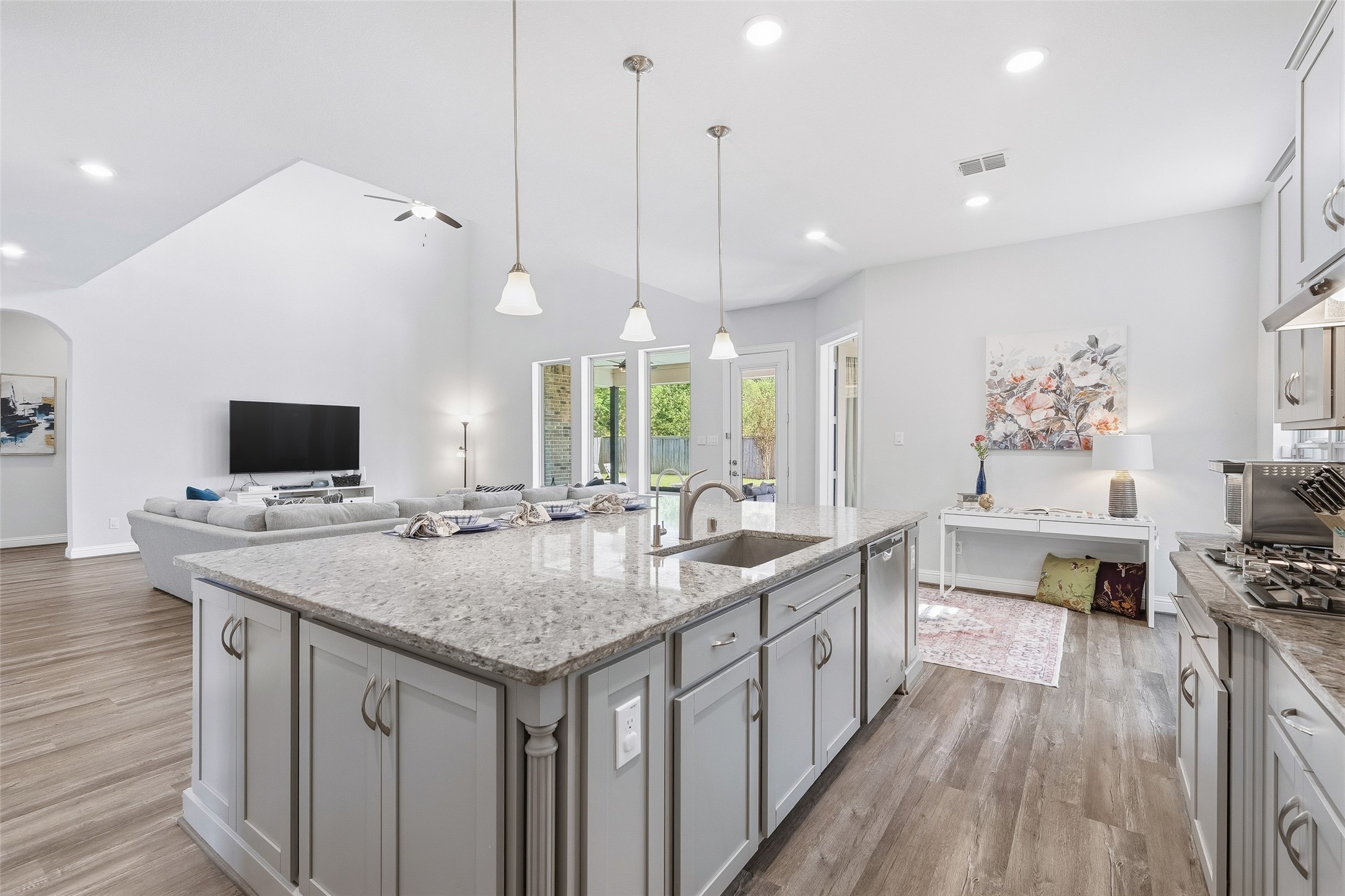 Enjoy an open-concept layout that flows seamlessly from the kitchen into the living area, enhanced by tall ceilings that create an airy, spacious atmosphere. Generous wall space easily accommodates large-scale artwork or an entertainment setup, while the granite island provides ample workspace, convenient storage on three sides, and comfortable barstool seating. The entire space overlooks the pool, creating a bright and inviting setting for everyday living and entertaining.