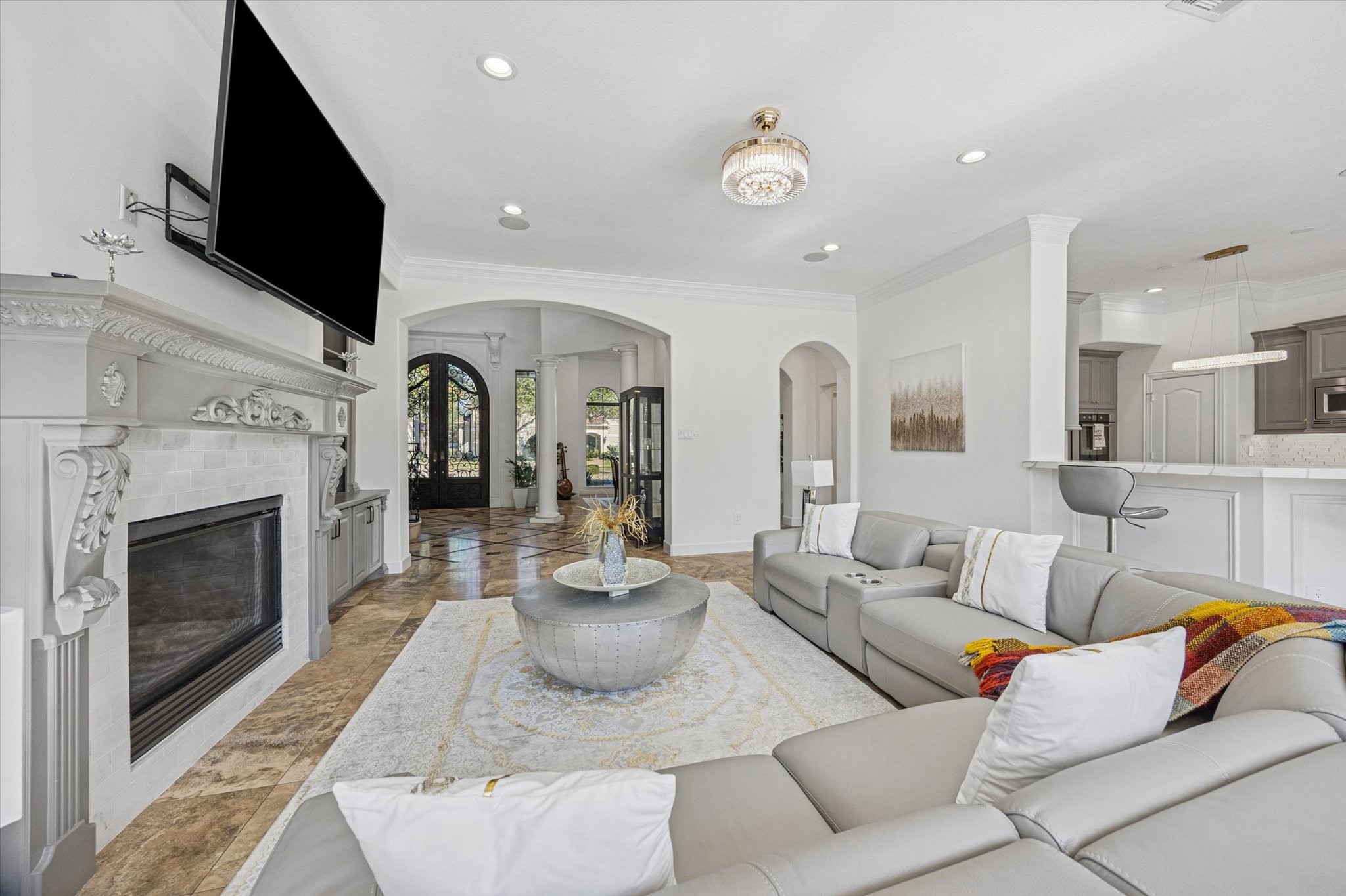 This spacious living room features a modern open layout with a cozy fireplace, The room flows seamlessly into the adjoining kitchen area, ideal for entertaining. High ceilings and large windows provide ample natural light.