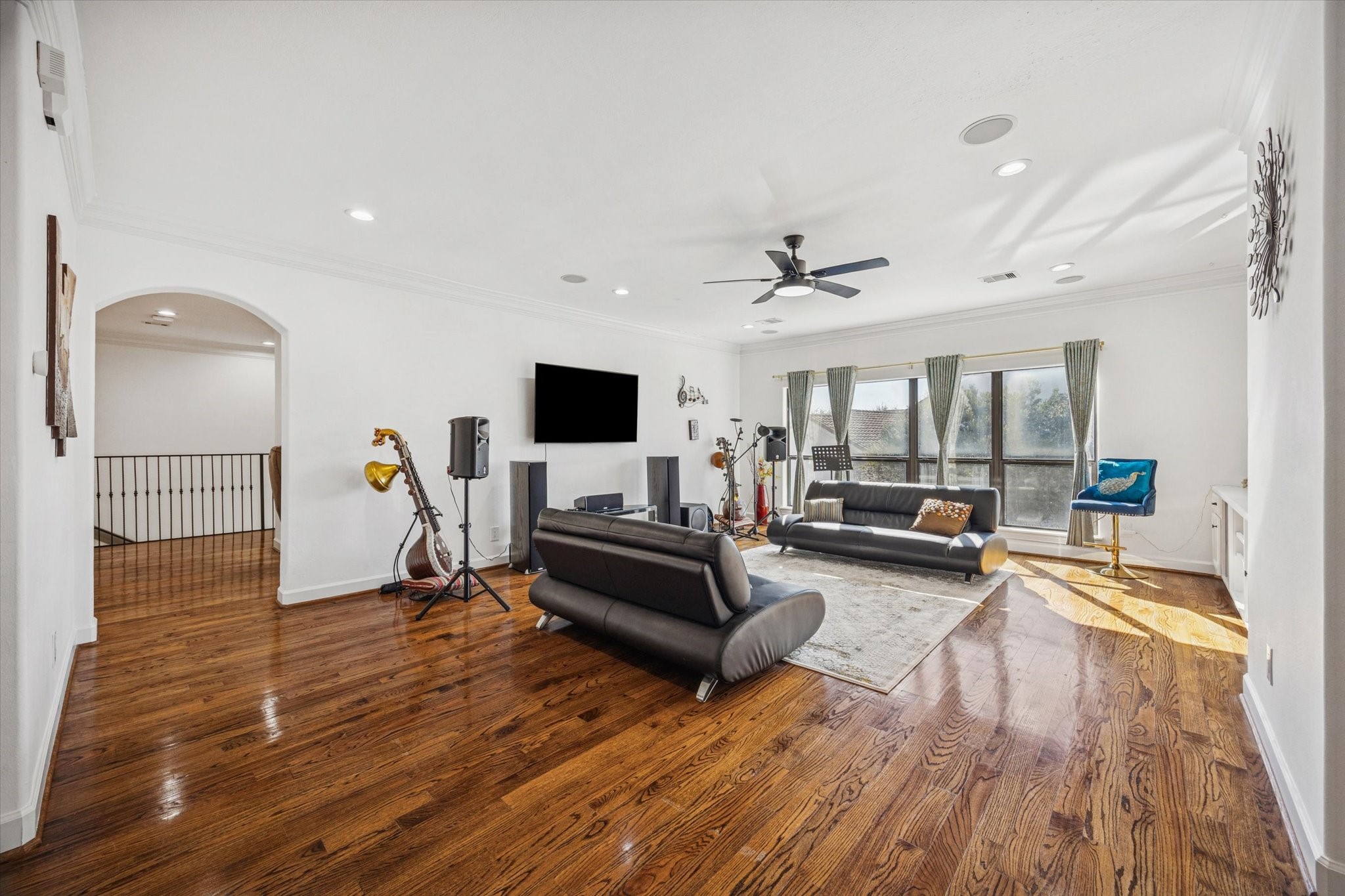 Spacious, modern upstairs game room with hardwood floors, large windows, and ample natural light. Features recessed lighting, ceiling fan, and built in speakers. Ideal for entertaining.