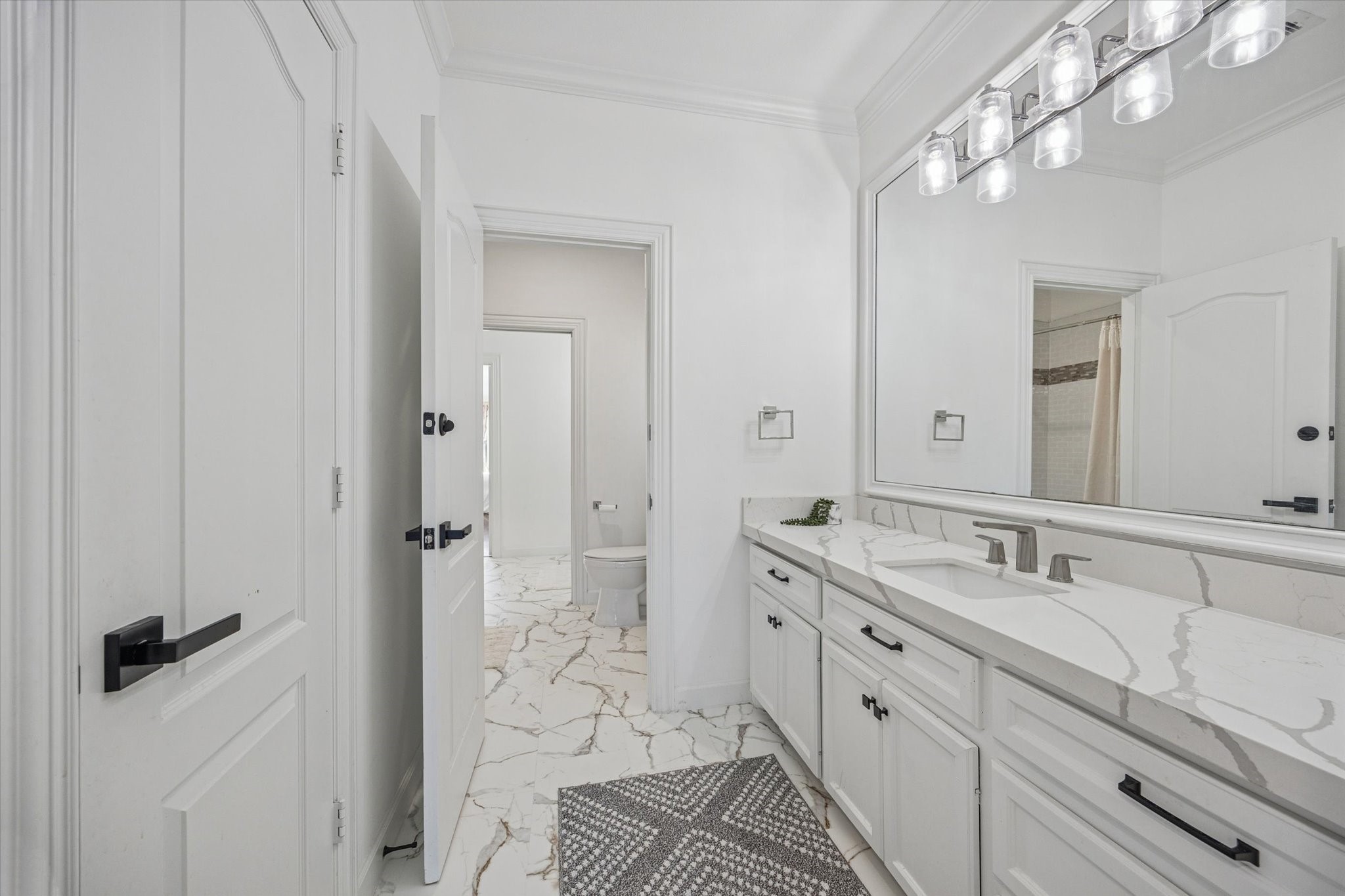 One of 2 upstairs adjoining jack and jill bathrooms. Bright and clean bathroom featuring a large mirror, sleek modern fixtures, and a spacious vanity with a quartz countertop.