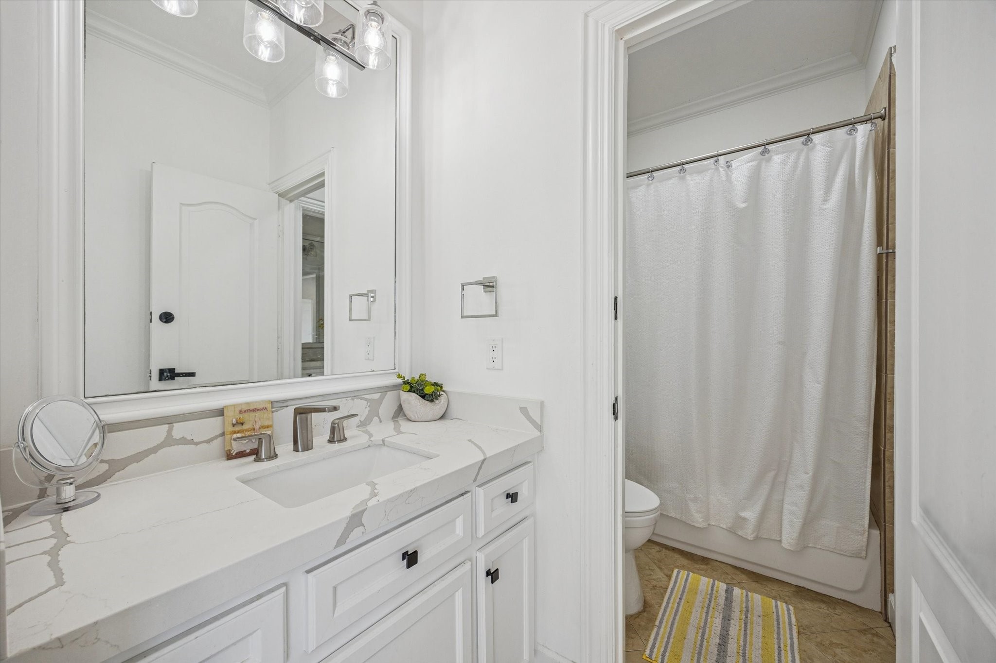 One of 2 upstairs adjoining jack and jill bathrooms. Bright and clean bathroom featuring a large mirror, sleek modern fixtures, and a spacious vanity with a quartz countertop.