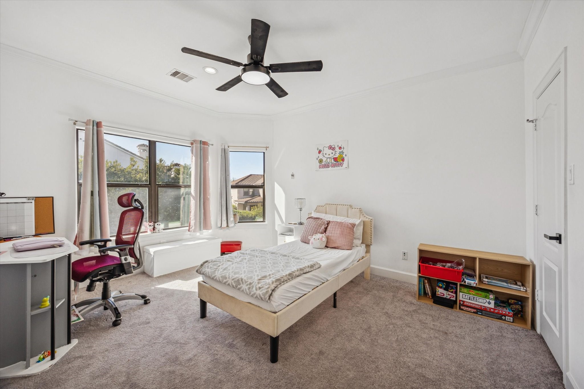 Bright and airy upstairs bedroom with carpeted flooring, a ceiling fan, and large windows offering ample natural light.