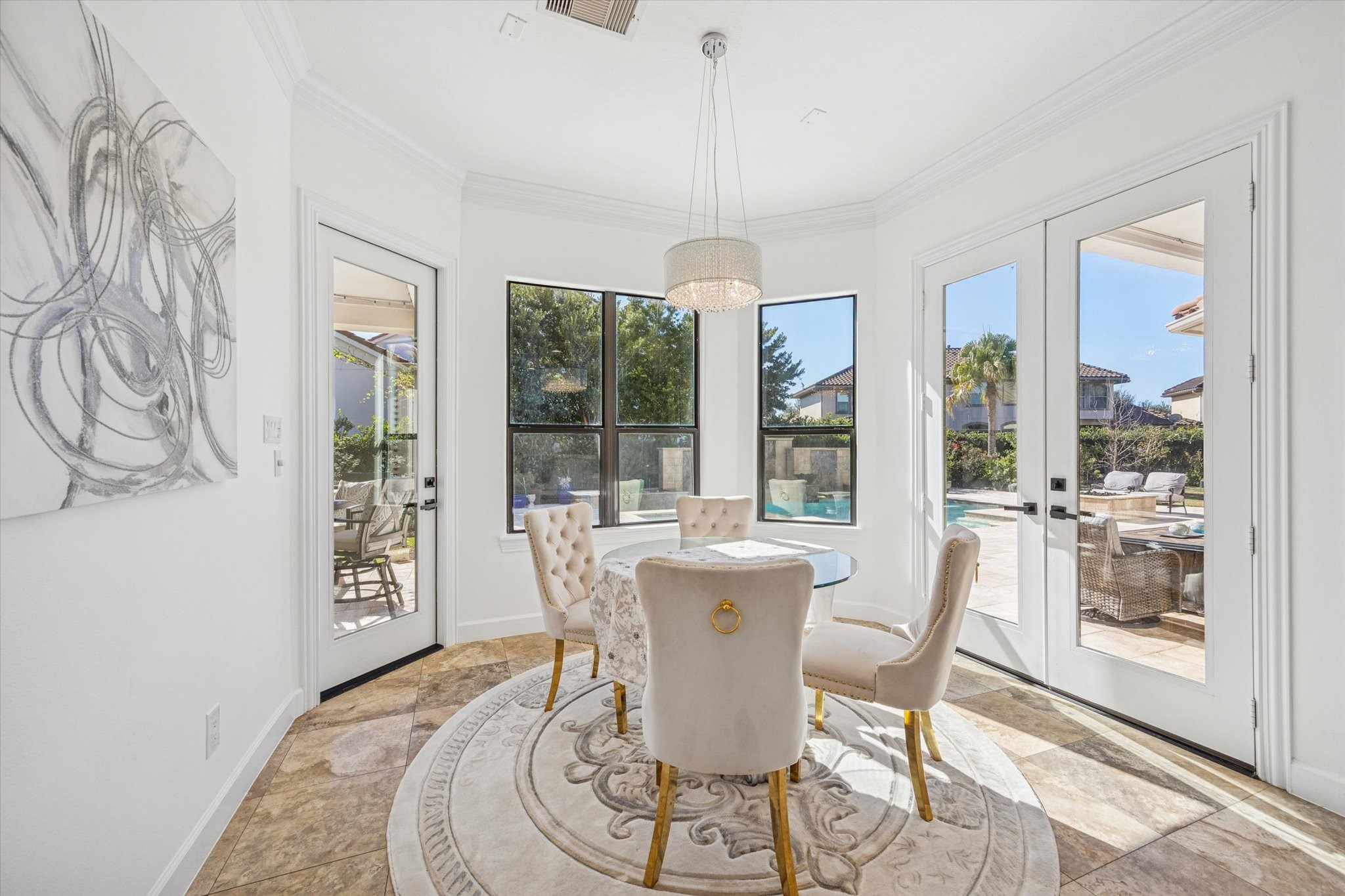 This bright breakfast area features large windows and glass door offer abundant natural light and views of a pool and patio, creating an inviting indoor-outdoor living experience.