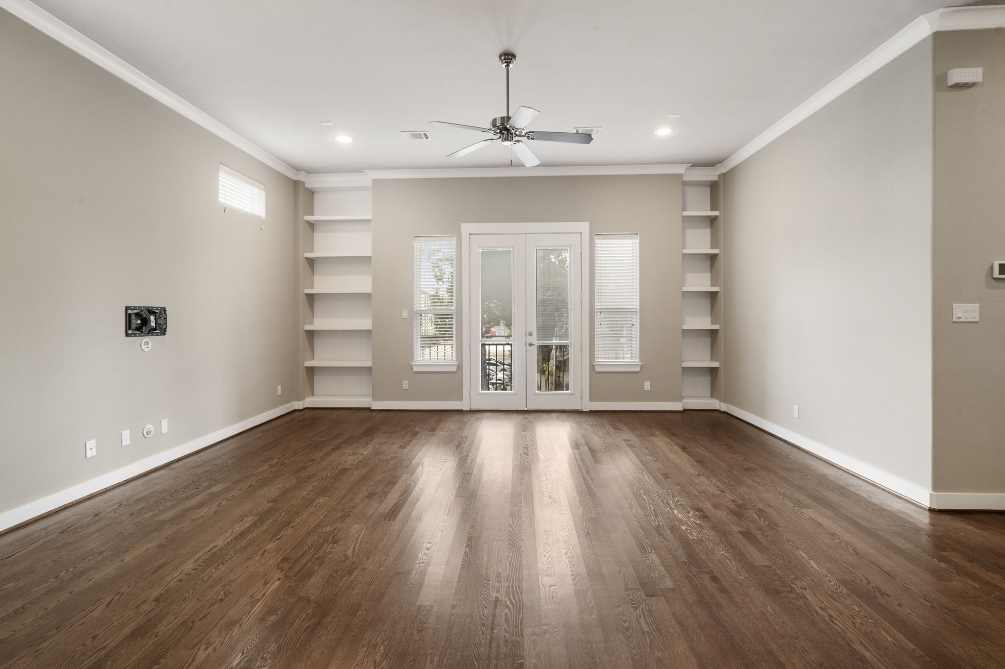 Open and airy living room featuring high ceilings, recessed LED lighting, and French doors that open to an exterior balcony.