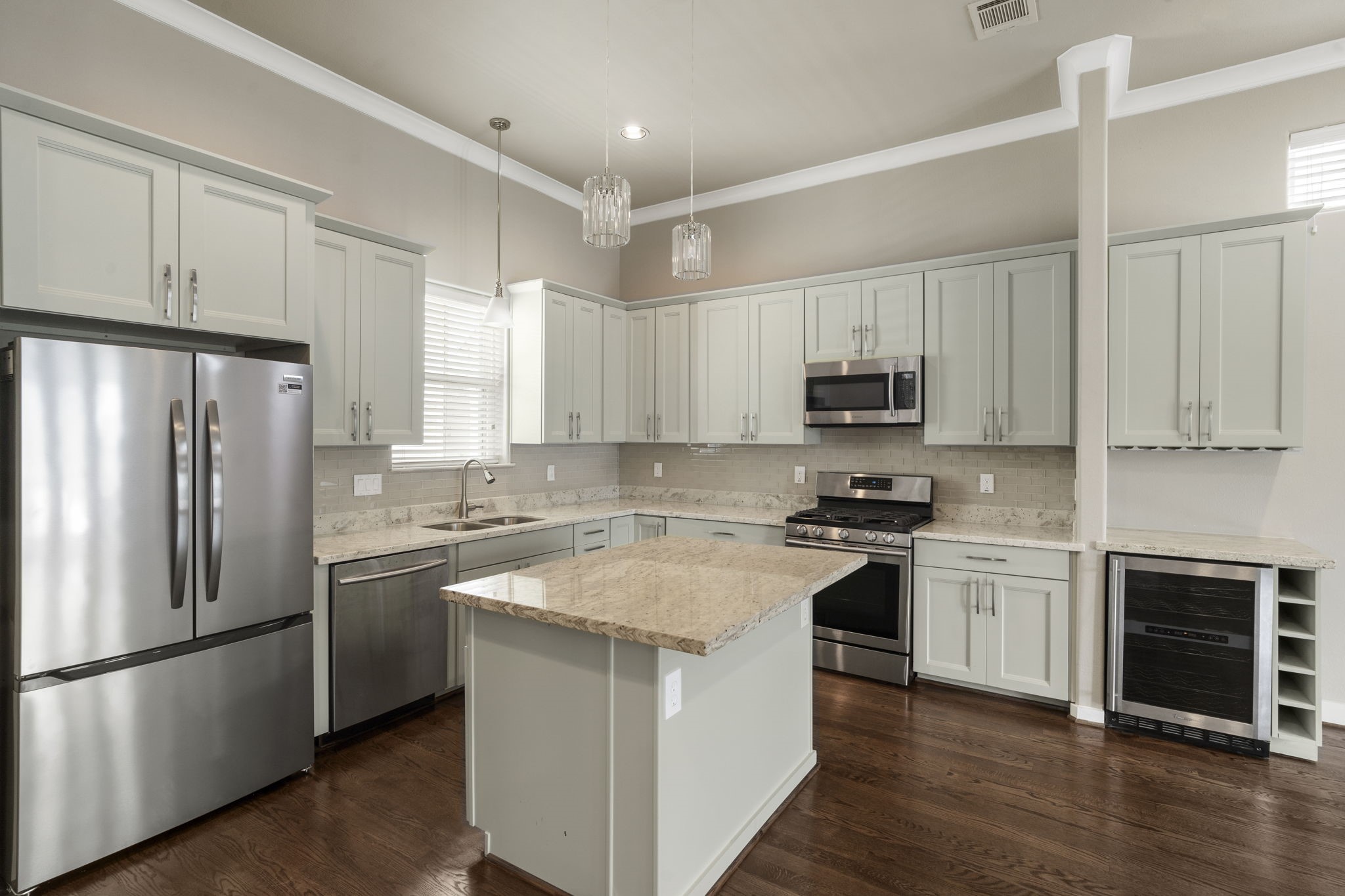 The center island provides additional food preparation space, ample storage, and a breakfast bar area, creating a functional hub for cooking, casual dining, and gathering.