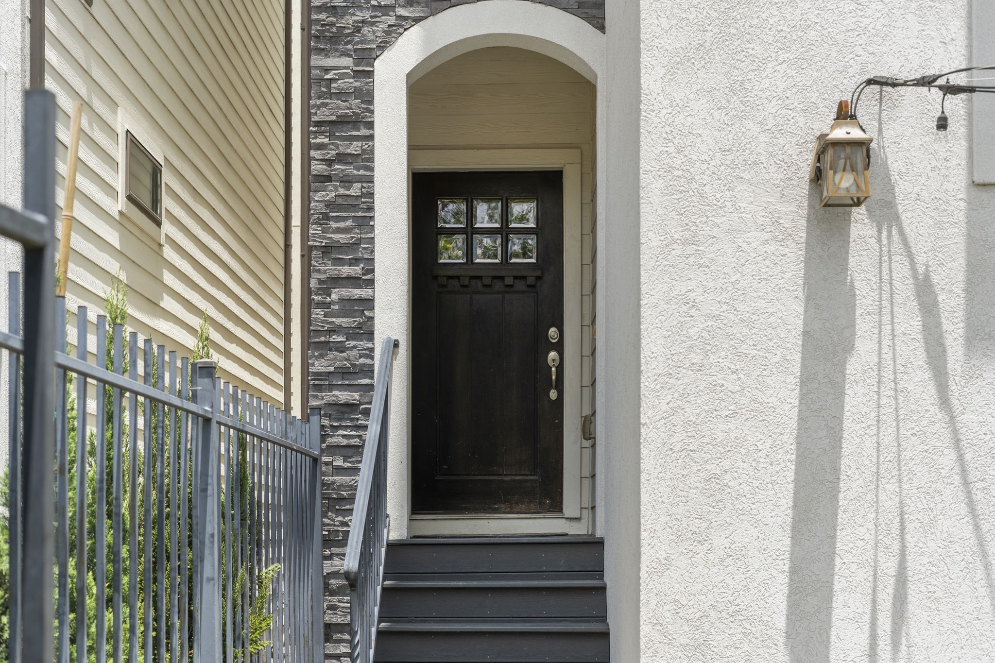 Modern stone and stucco exterior featuring a covered front entry and an inviting Craftsman-style front door that creates a warm and welcoming first impression.