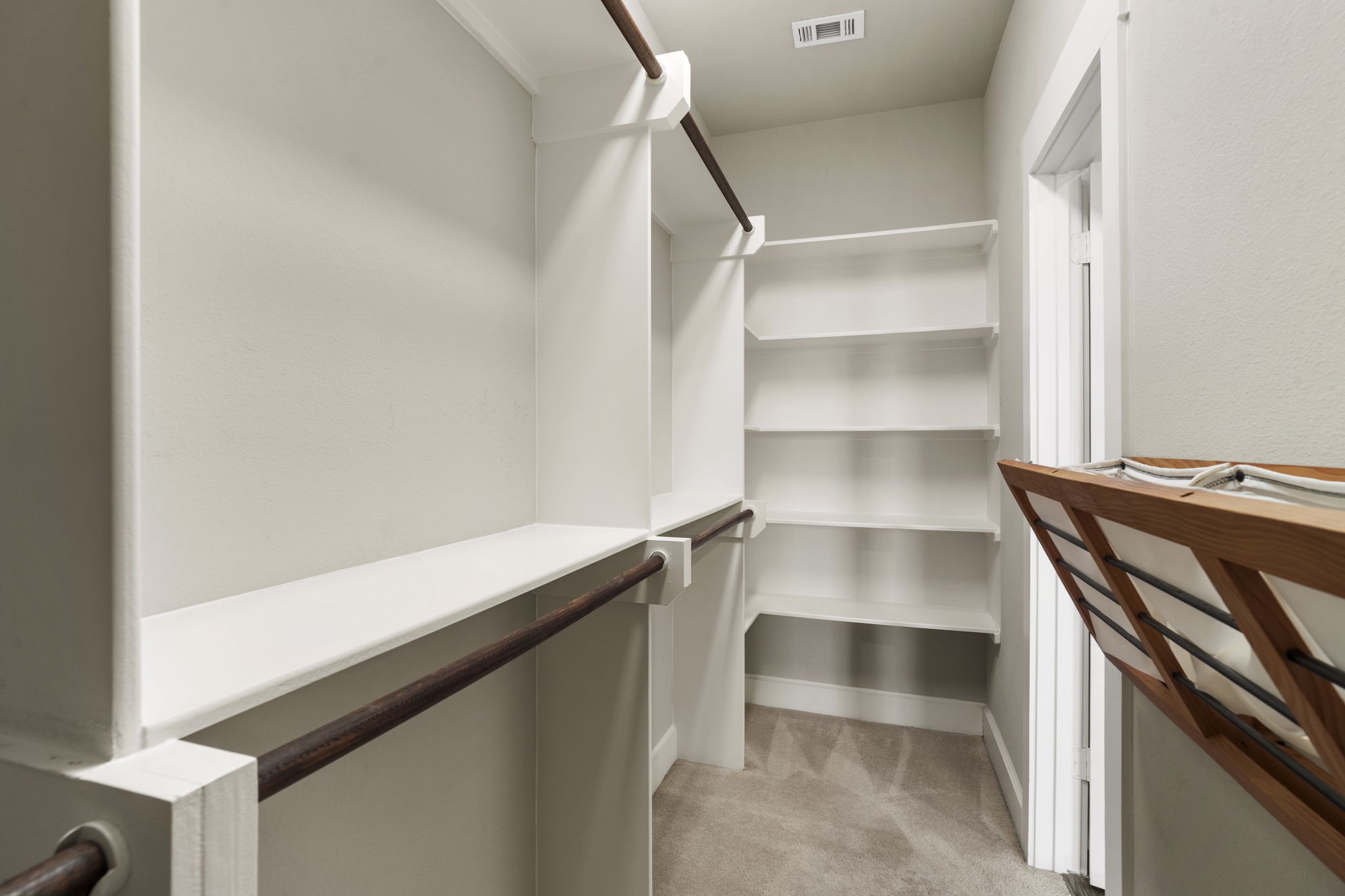 Large walk-in closet featuring dedicated hanging areas and built-in shelving provide ample storage.