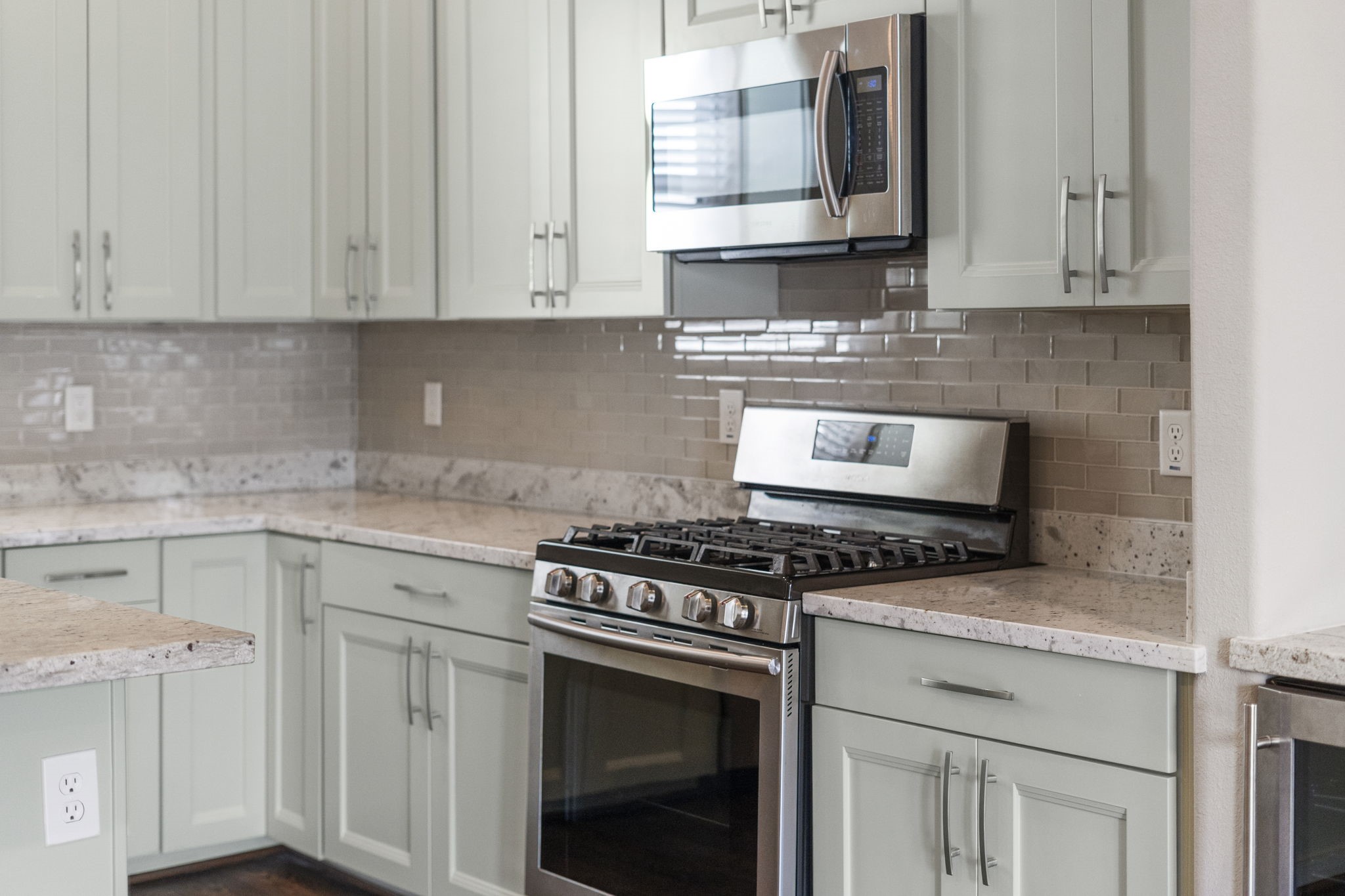 Timeless light granite countertops paired with a glass subway tile backsplash create a bright and elegant kitchen design.
