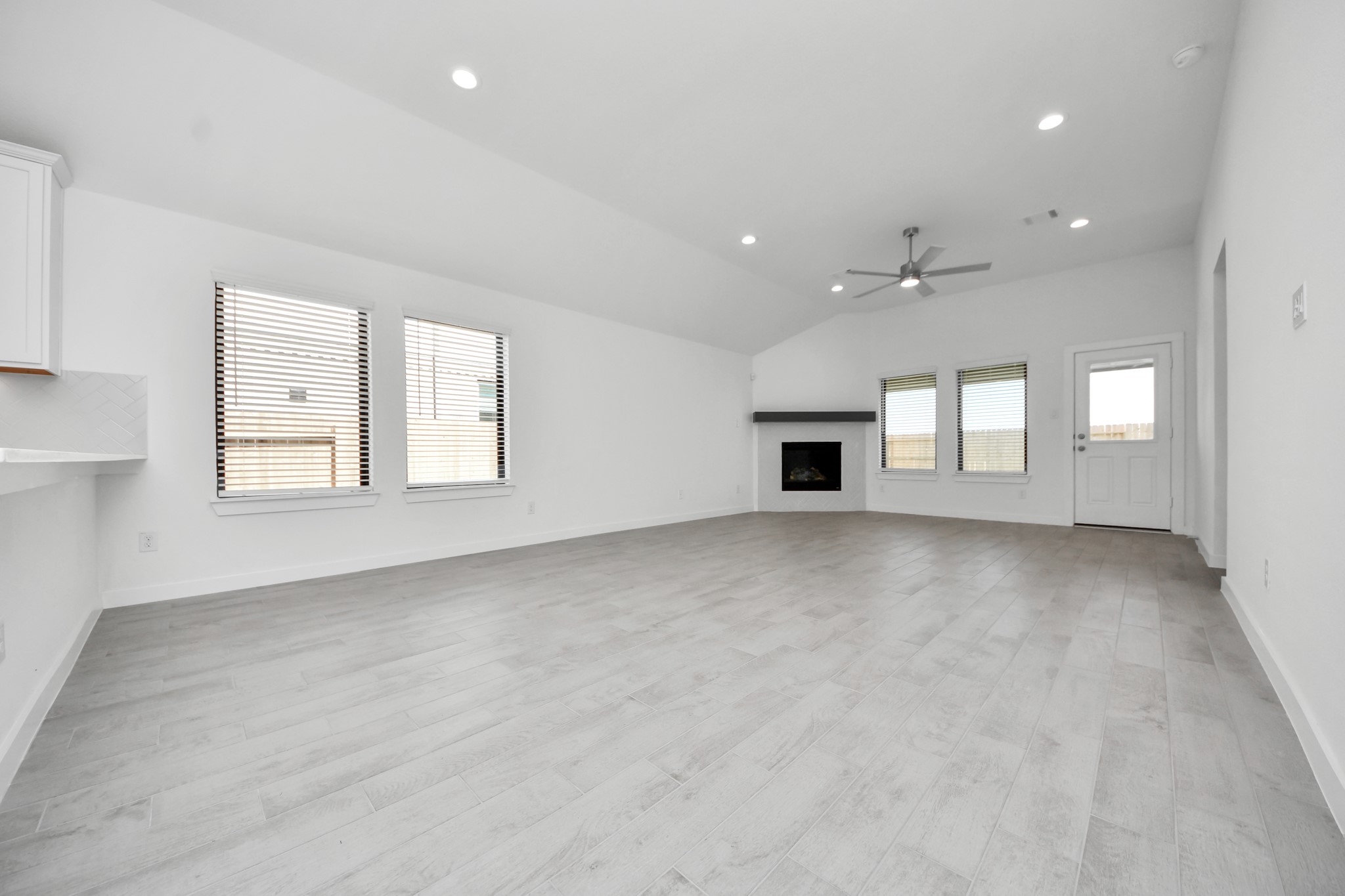 Welcome family and guests to your charming living room! With its high ceilings, recessed lighting, ceiling fan, custom paint, beautiful flooring, and large windows that let in abundant natural light, this room is perfect for gatherings.