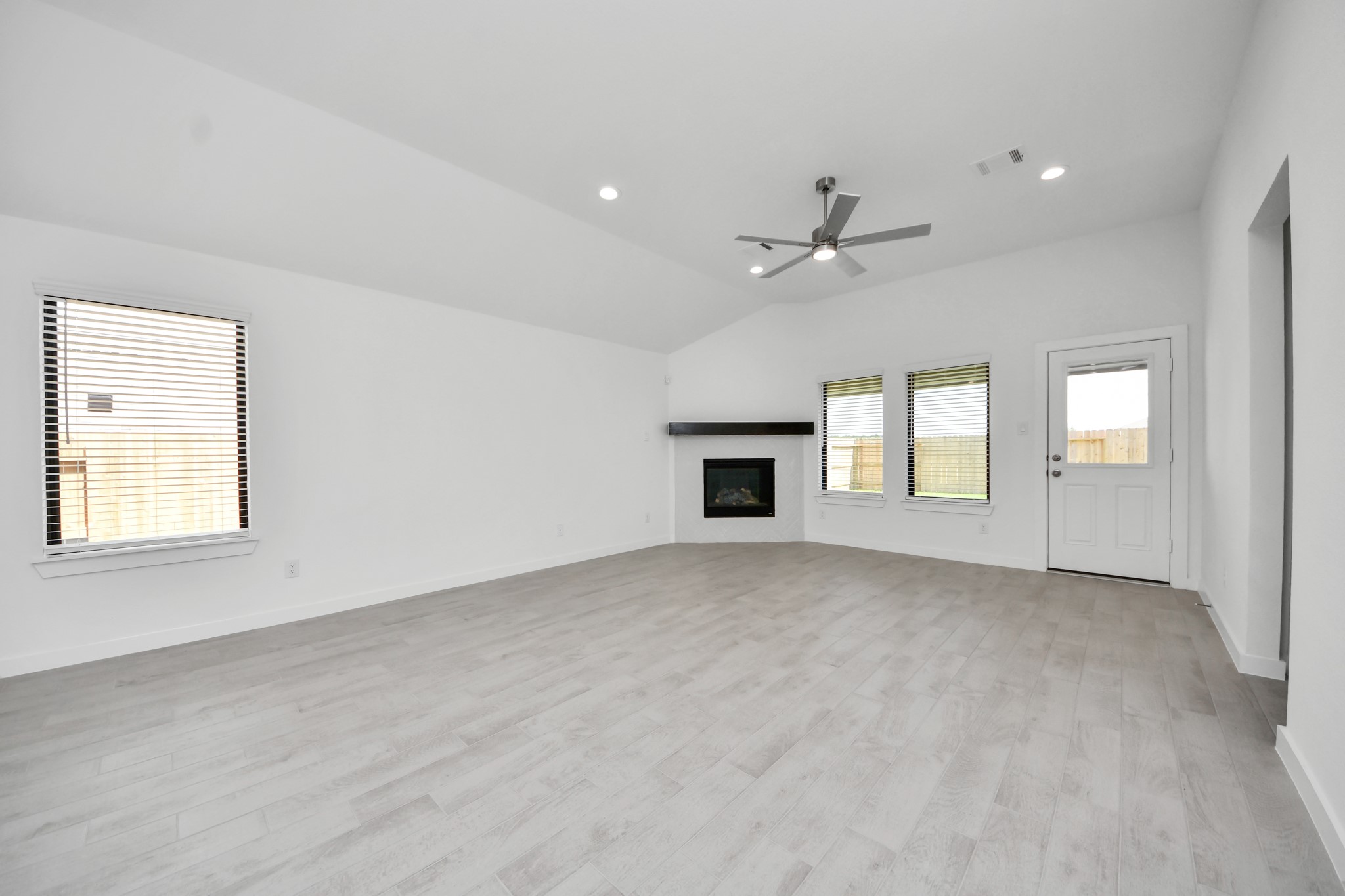Family room flooded with natural light through the expansive windows.  The premium tile flooring adds a touch of luxury to the space, creating the perfect setting for relaxing moments and cherished gatherings with loved ones