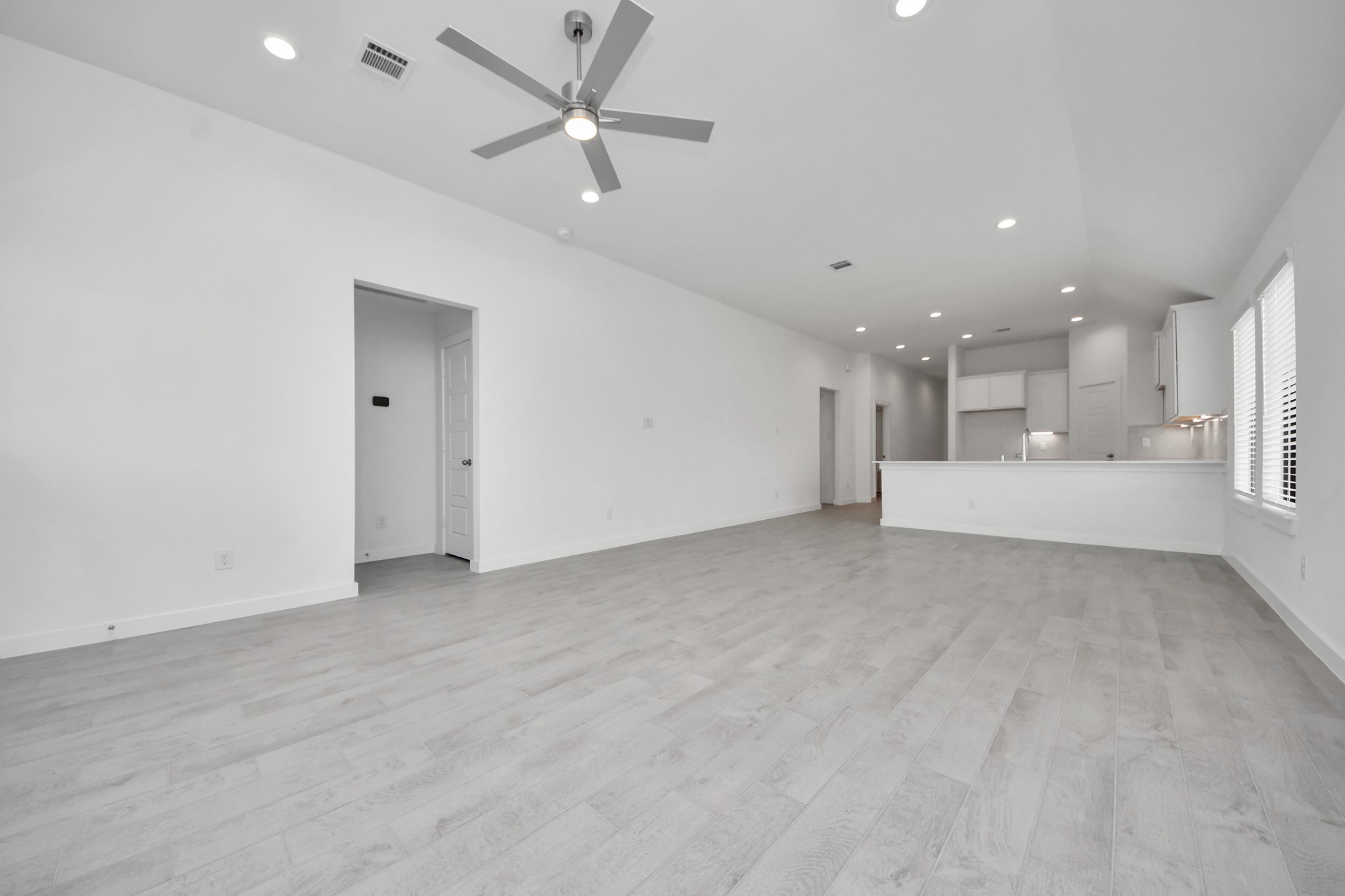 Relax and unwind in this inviting family room, illuminated by abundant natural light streaming in through tall windows, complemented by high ceilings and stunning flooring. Stay comfortable year-round with the gentle breeze from the ceiling fan, creating the perfect atmosphere for family gatherings.