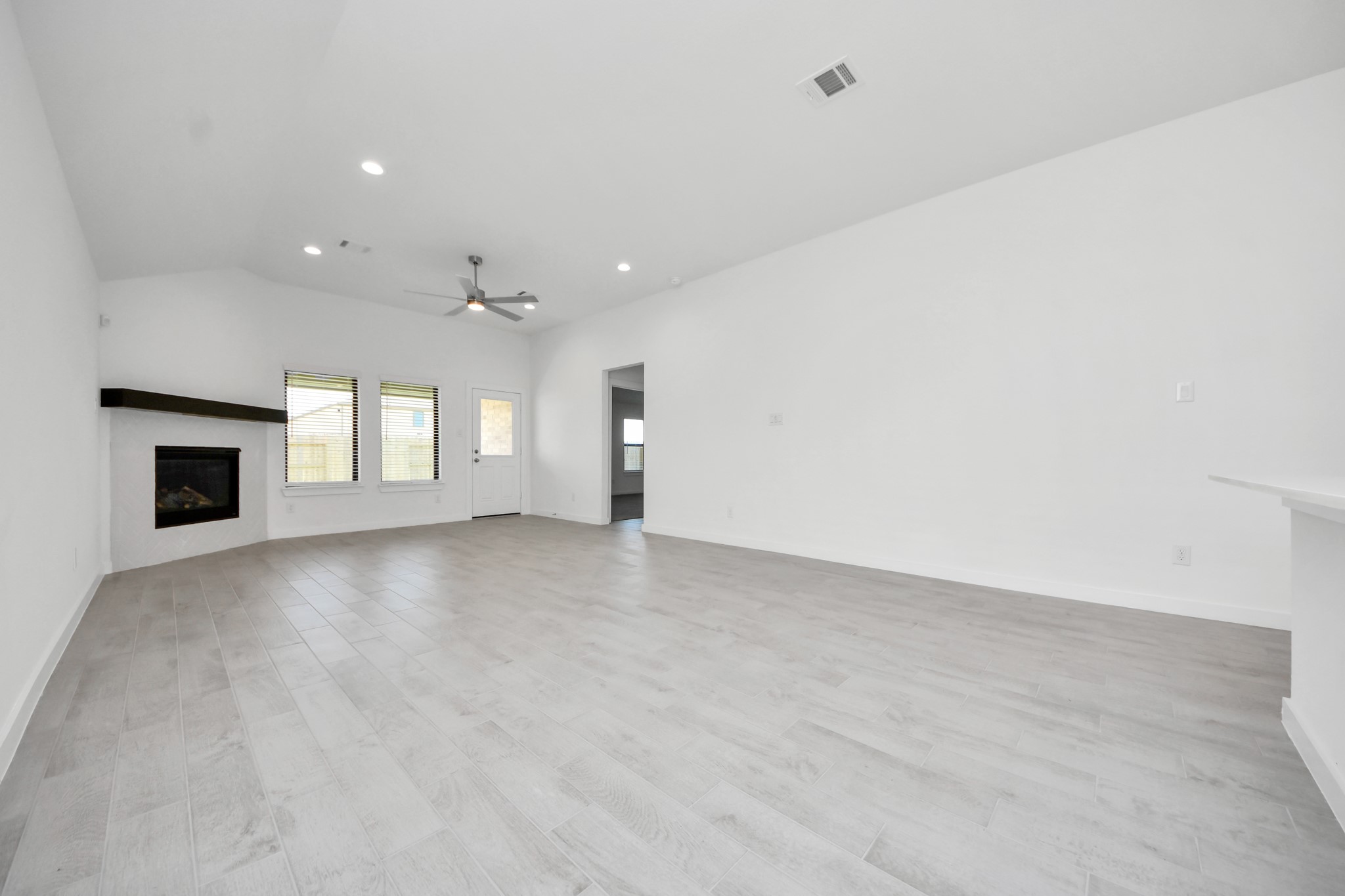 Bring your loved ones and guests together in the inviting living room! Boasting lofty high ceilings, recessed lighting, a stylish ceiling fan, custom paint, stunning flooring, and expansive windows that flood the space with ample natural light all day long.