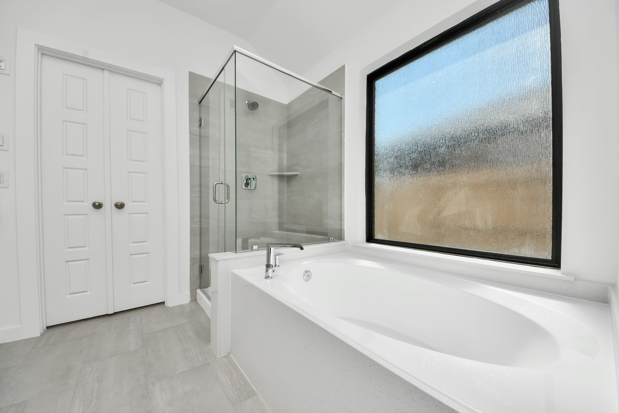Escape to a spa-like oasis in this primary bathroom. Enjoy a walk-in shower with tile surround, a separate garden tub with custom detailing, and an elegant vanity featuring light countertops, modern hardware, and beautiful vanity lights. Experience luxury and relaxation in every detail.