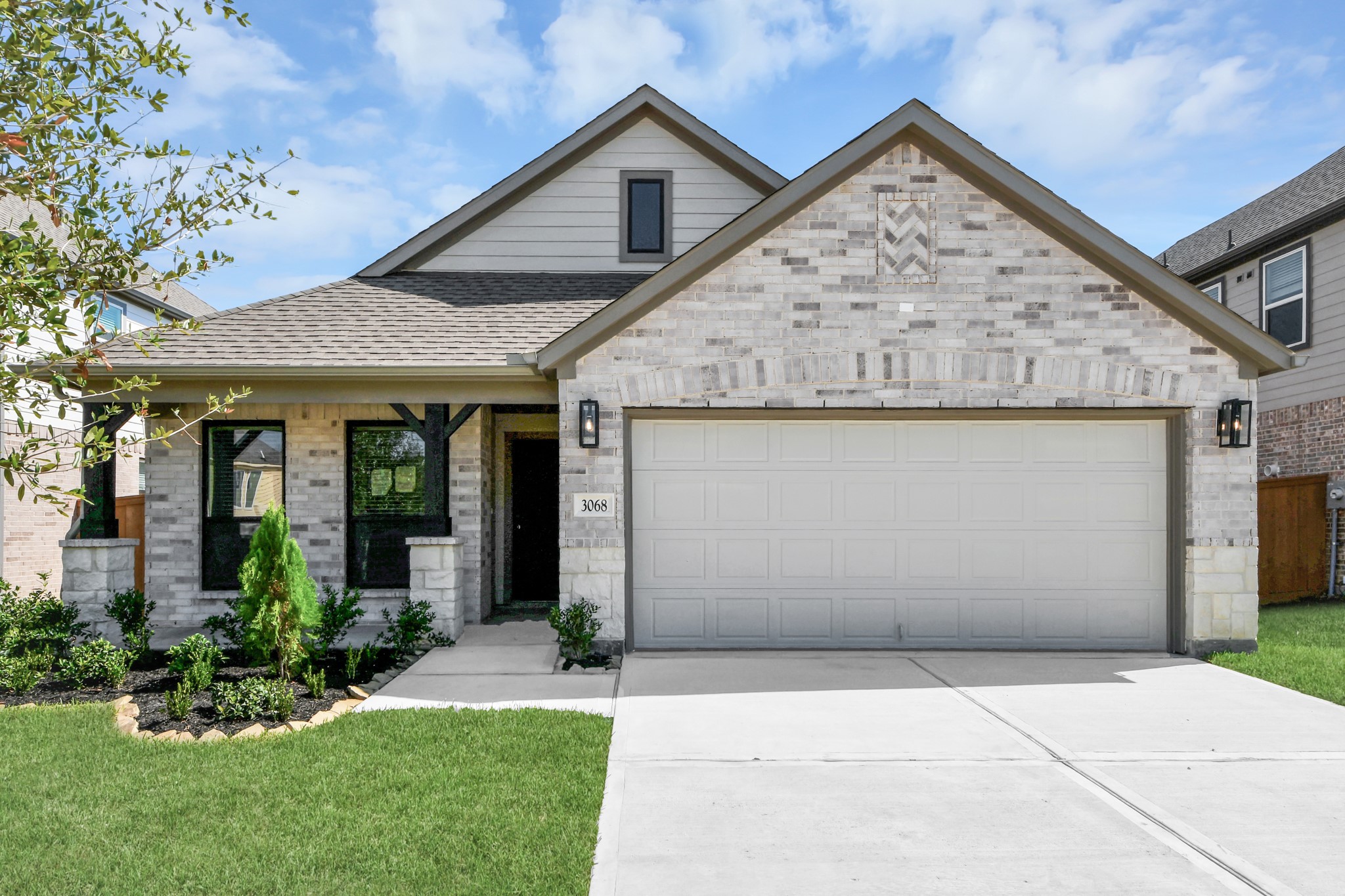 Meticulously maintained yard and lush landscape, paired with a premium elevation featuring captivating brick accents. Modern coach lights add a touch of contemporary elegance to the exterior.