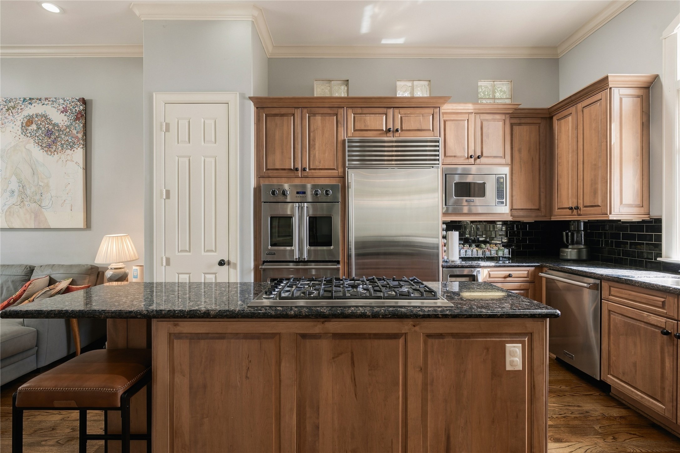 At the center, an oversized island creates a true working kitchen, pairing generous prep space with a gas cooktop and seating for casual meals.