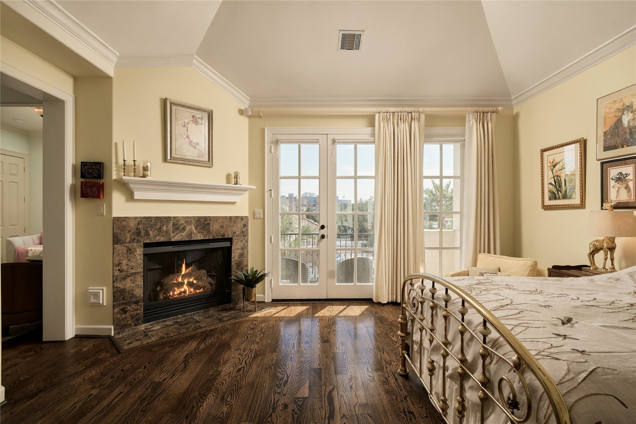French doors connect the primary directly to its private balcony, while the fireplace brings a sense of warmth and intimacy to an otherwise expansive retreat.