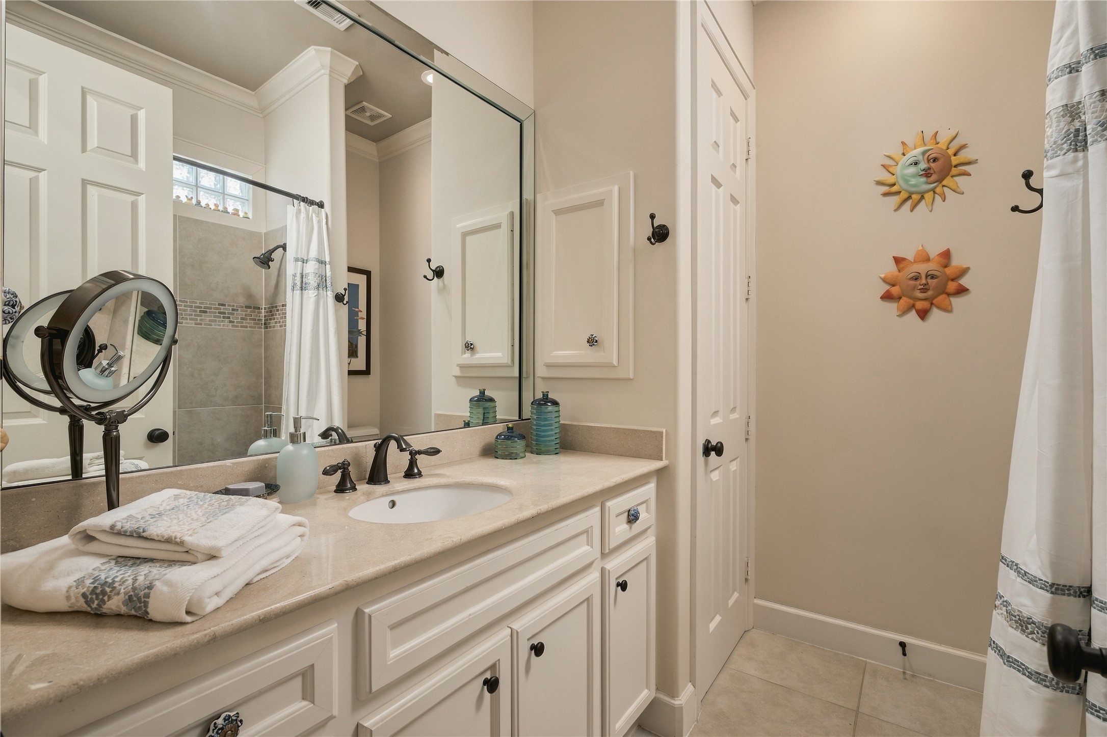 A second full bath completes the first-floor guest accommodations, with a generous vanity, tiled tub and shower, and additional built-in storage.