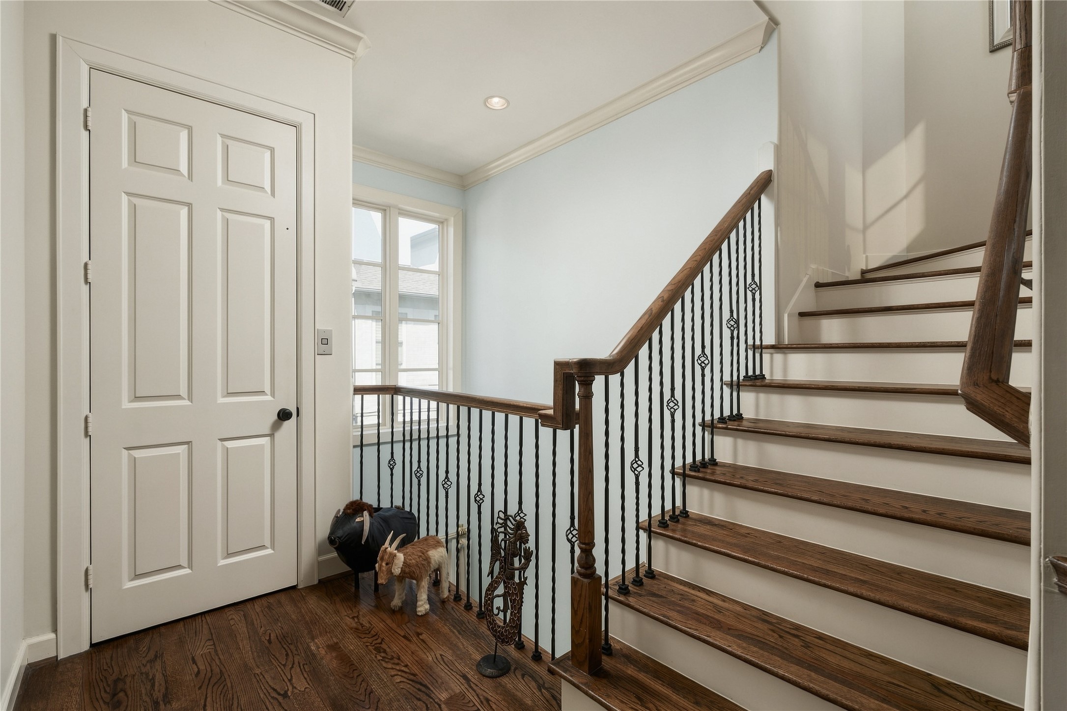 Hardwood stairs and iron balusters carry the homes architectural detailing upward as the tour transitions from the shared living spaces to the private rooms above.