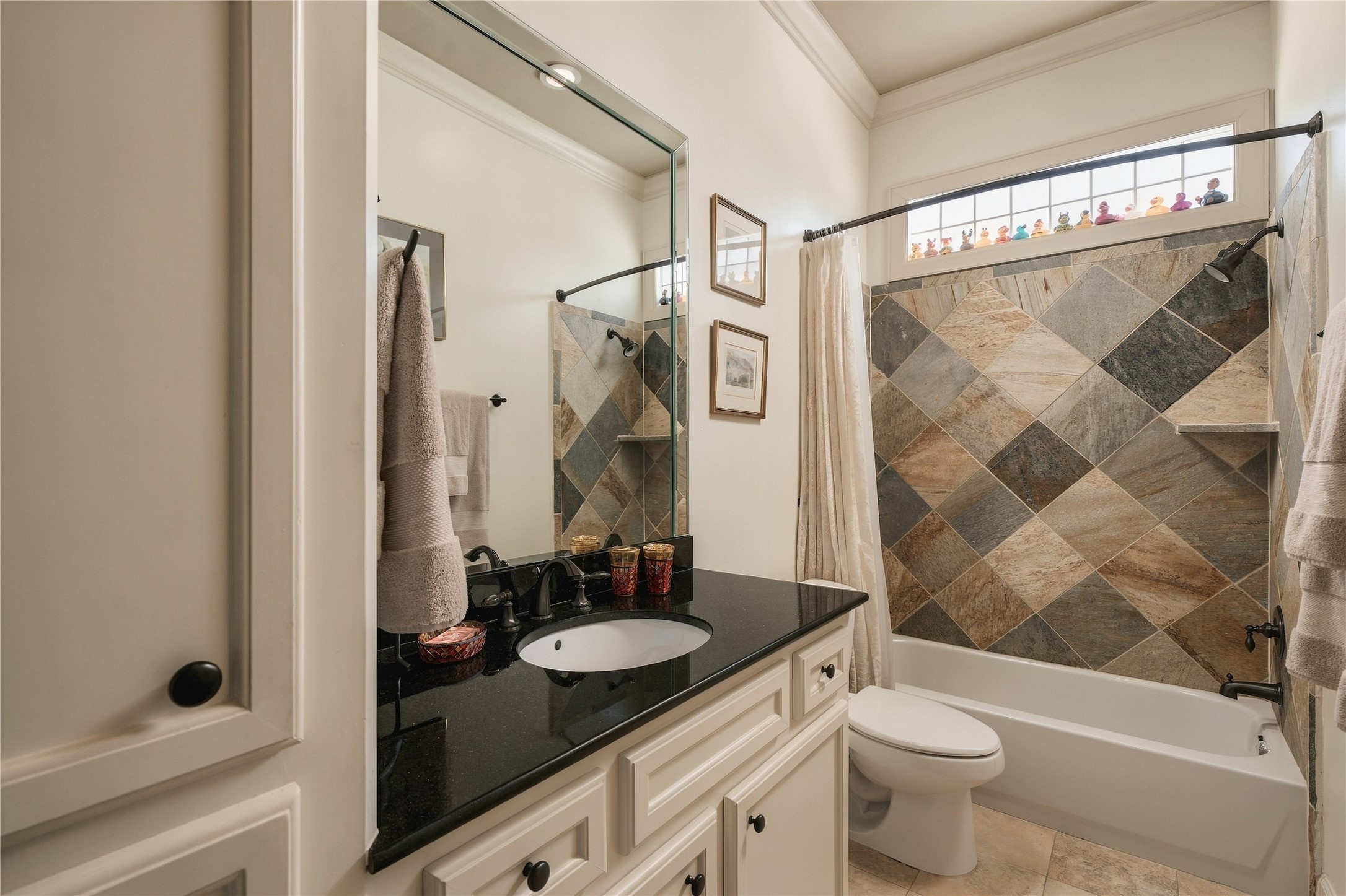 The adjoining bath brings in a richer material moment, with a granite-topped vanity and patterned stone surrounding the tub and shower.