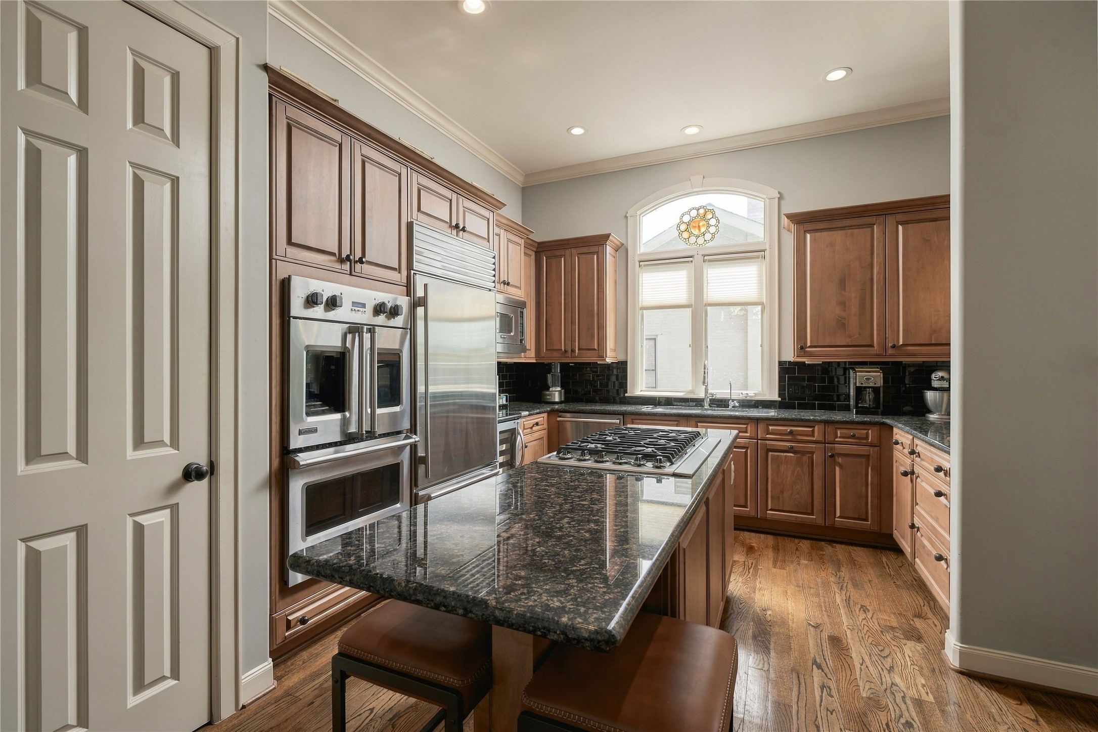 Theres room here for the way a kitchen actually gets used; cooking at the island, someone pulling up a stool, and conversation carrying in from the adjoining living spaces.