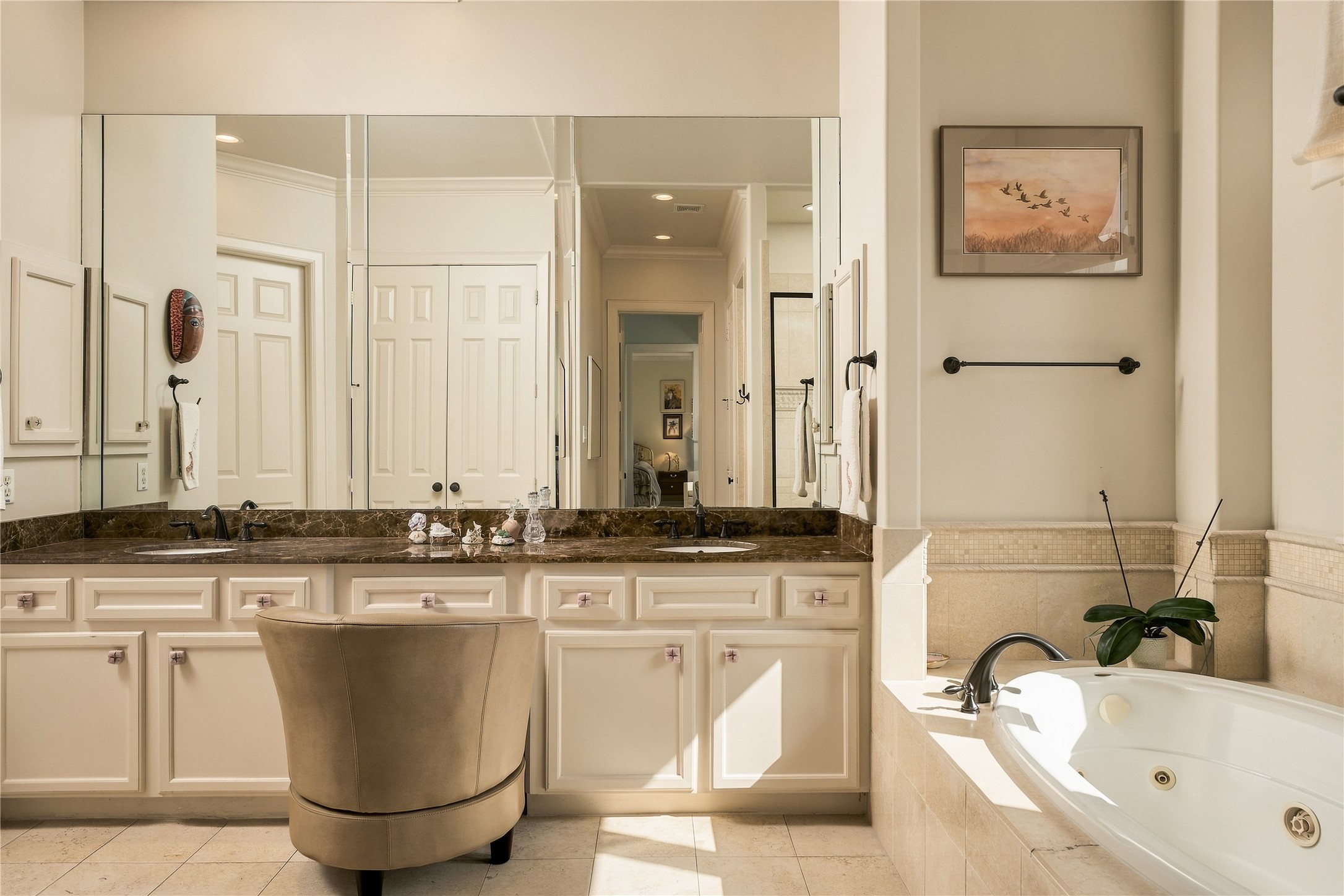 The primary bath continues the scale of the suite with an extended dual-sink vanity, dedicated seated vanity space and a jetted soaking tub surrounded in stone.