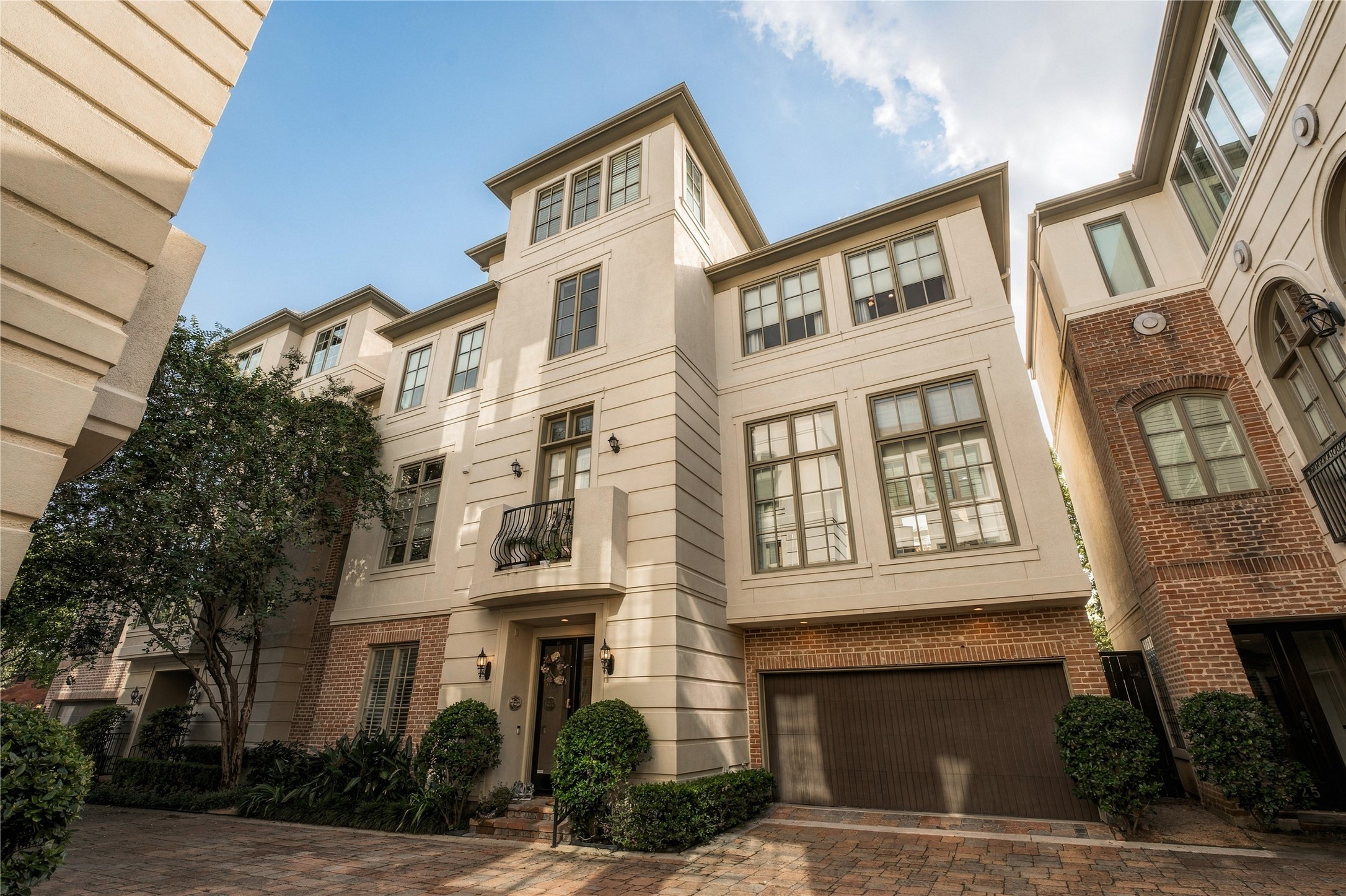 A wider perspective shows how the home settles into the intimate community, with mature landscaping, traditional detailing and a tucked-away feel that contrasts with the city just beyond it.